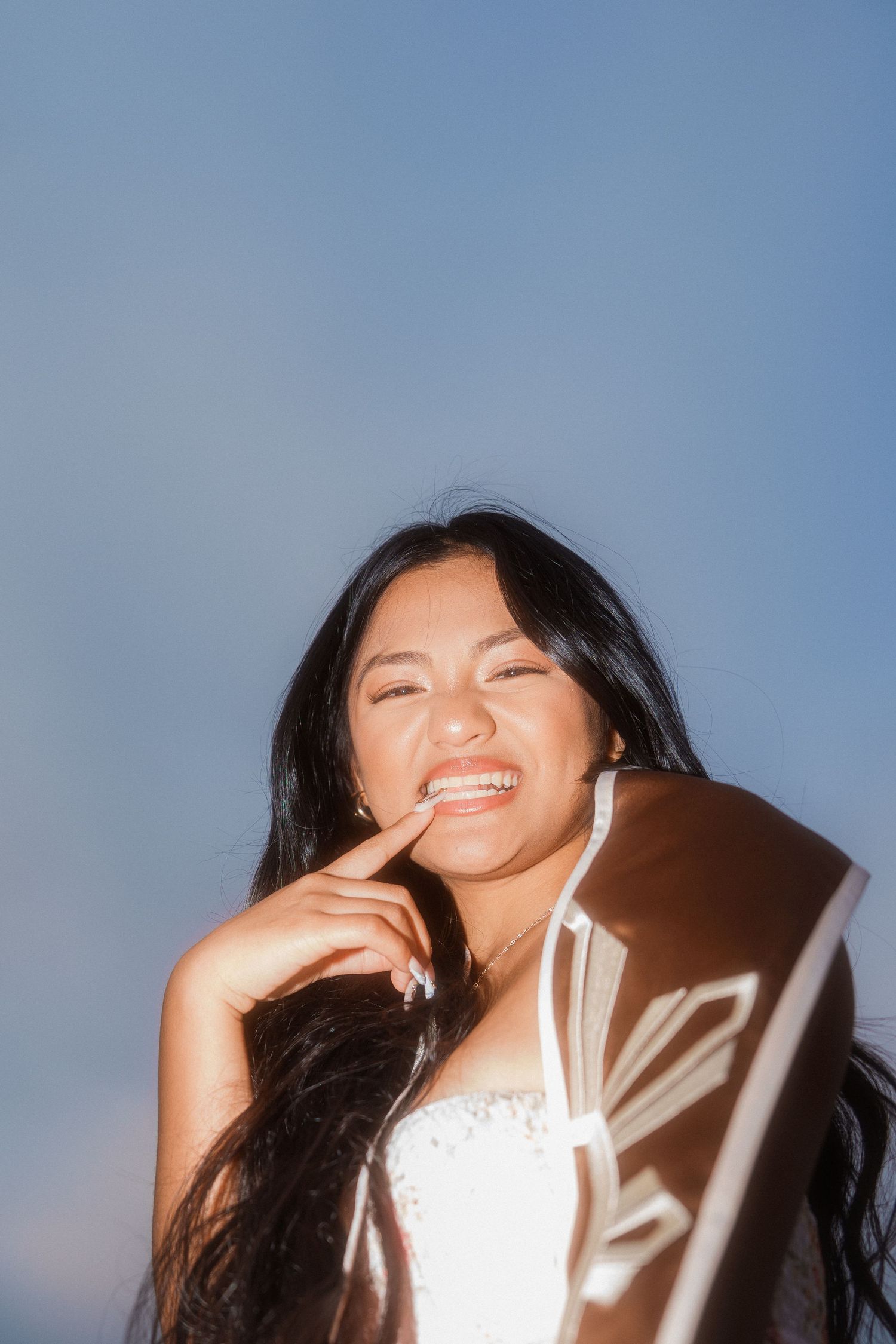 girl biting her fingernail while smiling and looking at the camera for a graduation photo