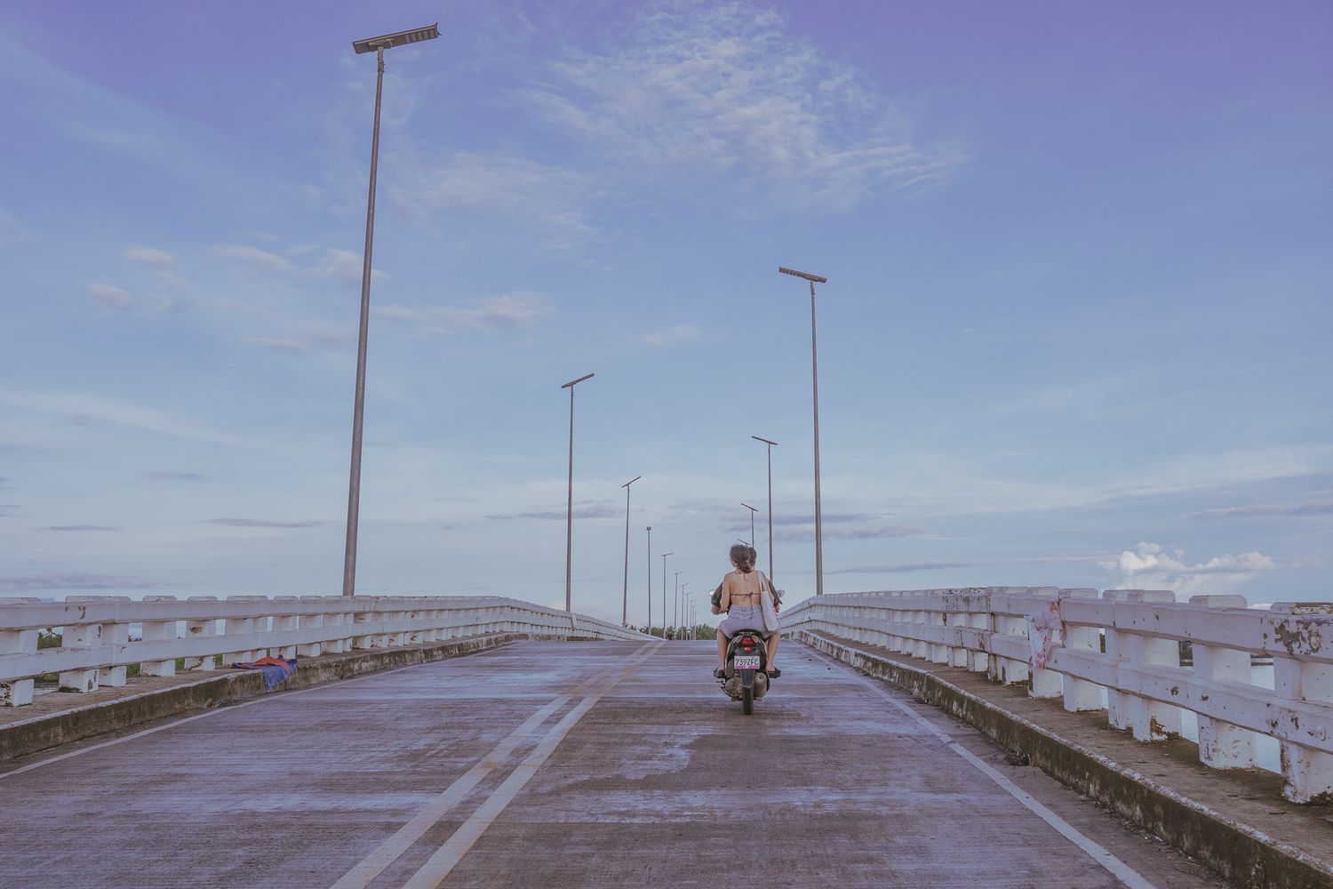 couple on a bridge in siargao riding a motorcycle