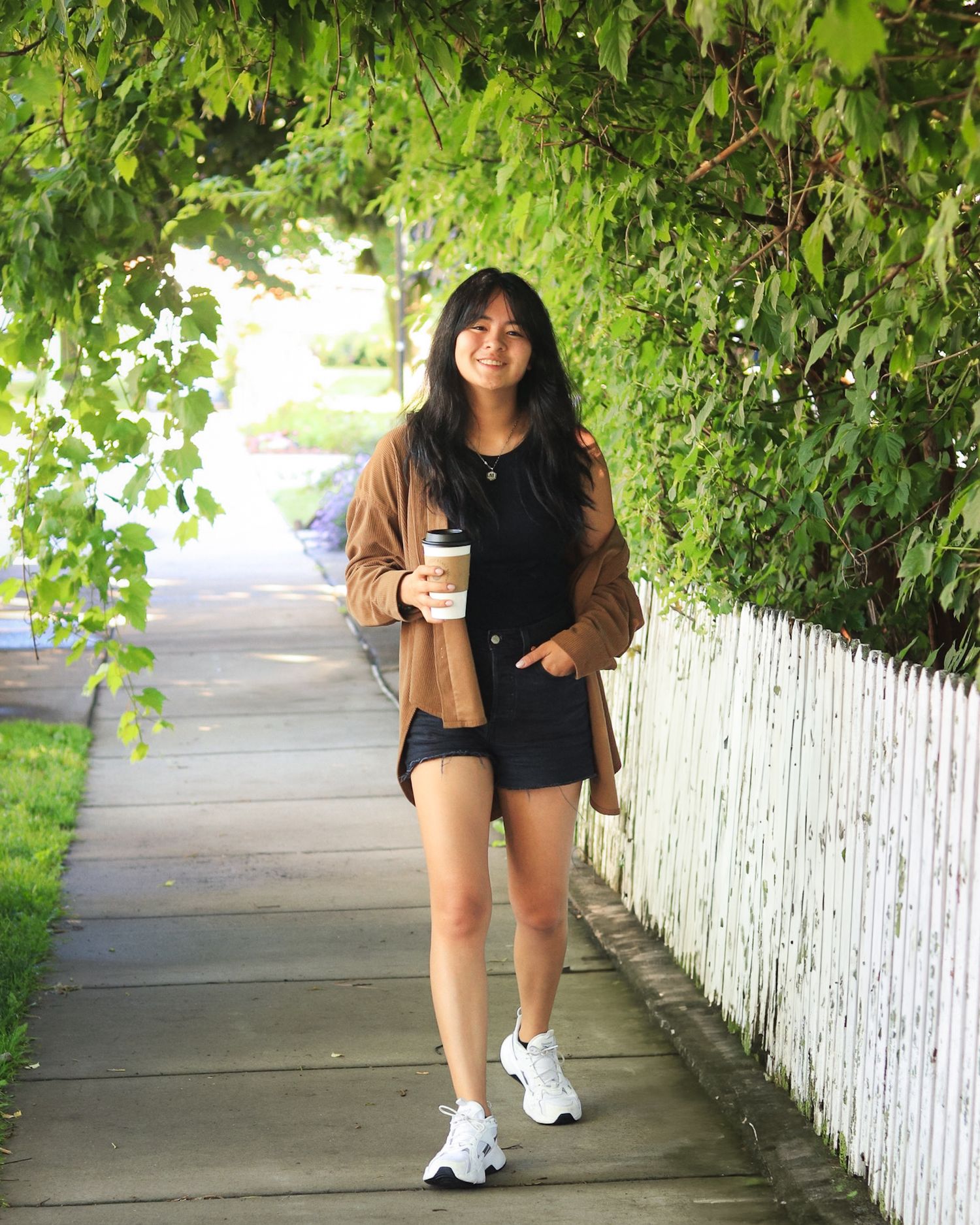 Girl posing and walking down sidewalk with coffee