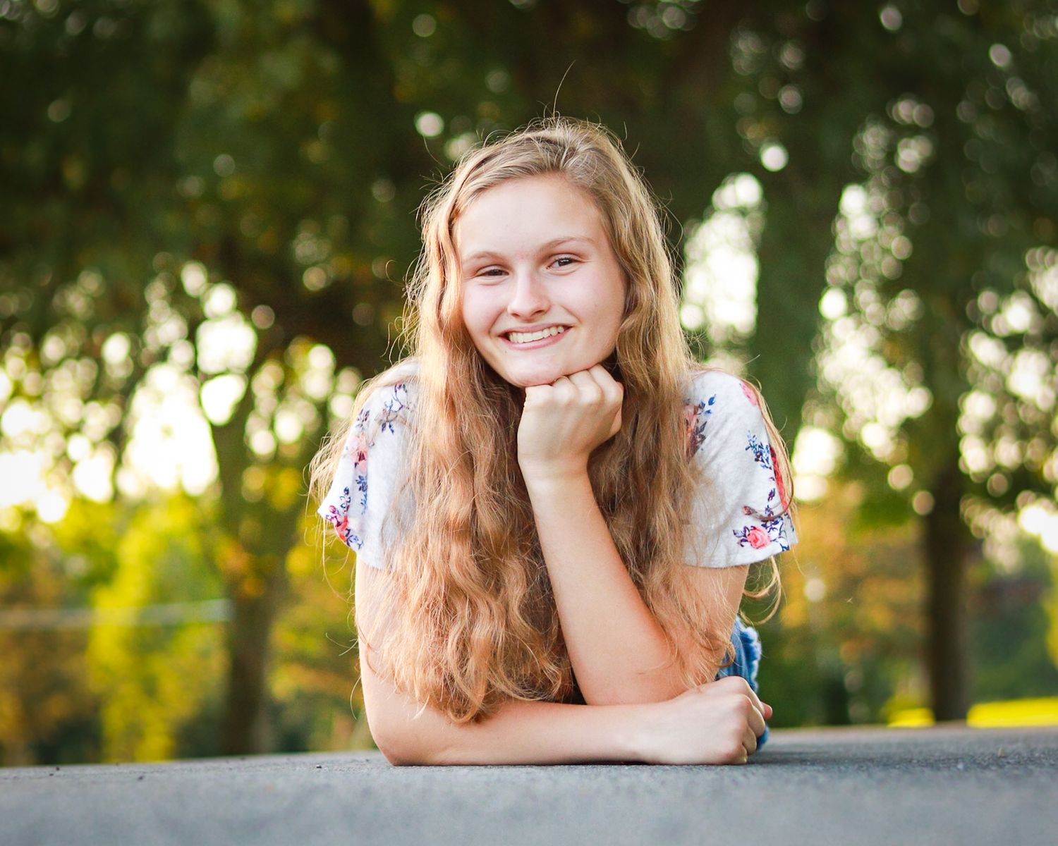 A girl smiling at the camera while lying on the road