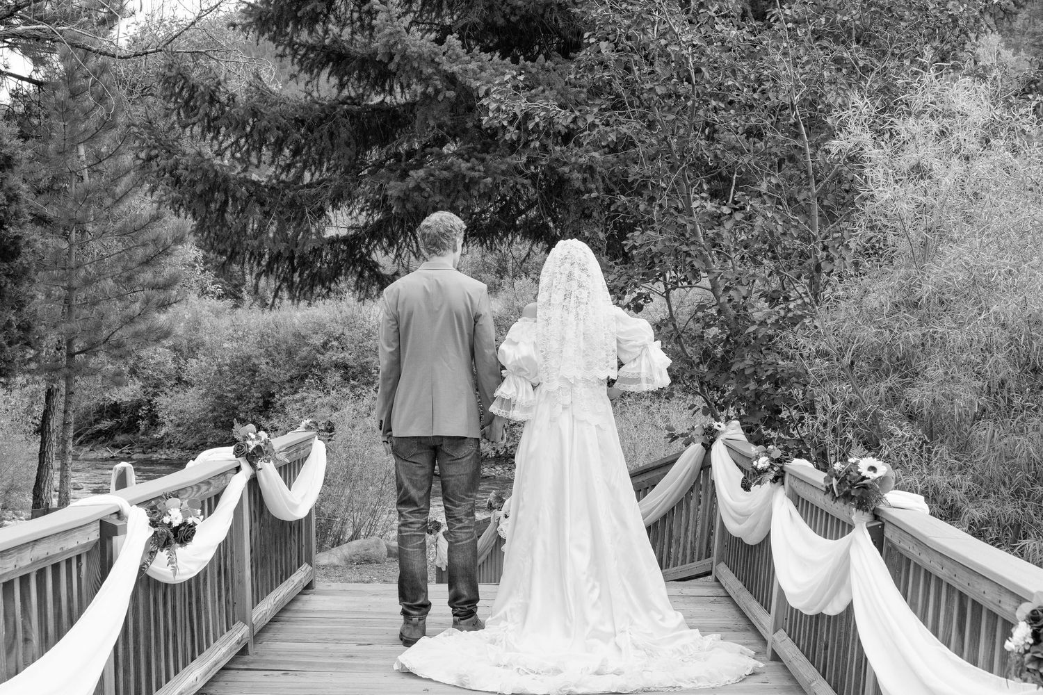 A bride and groom walking away on a decorated wooden bridge.