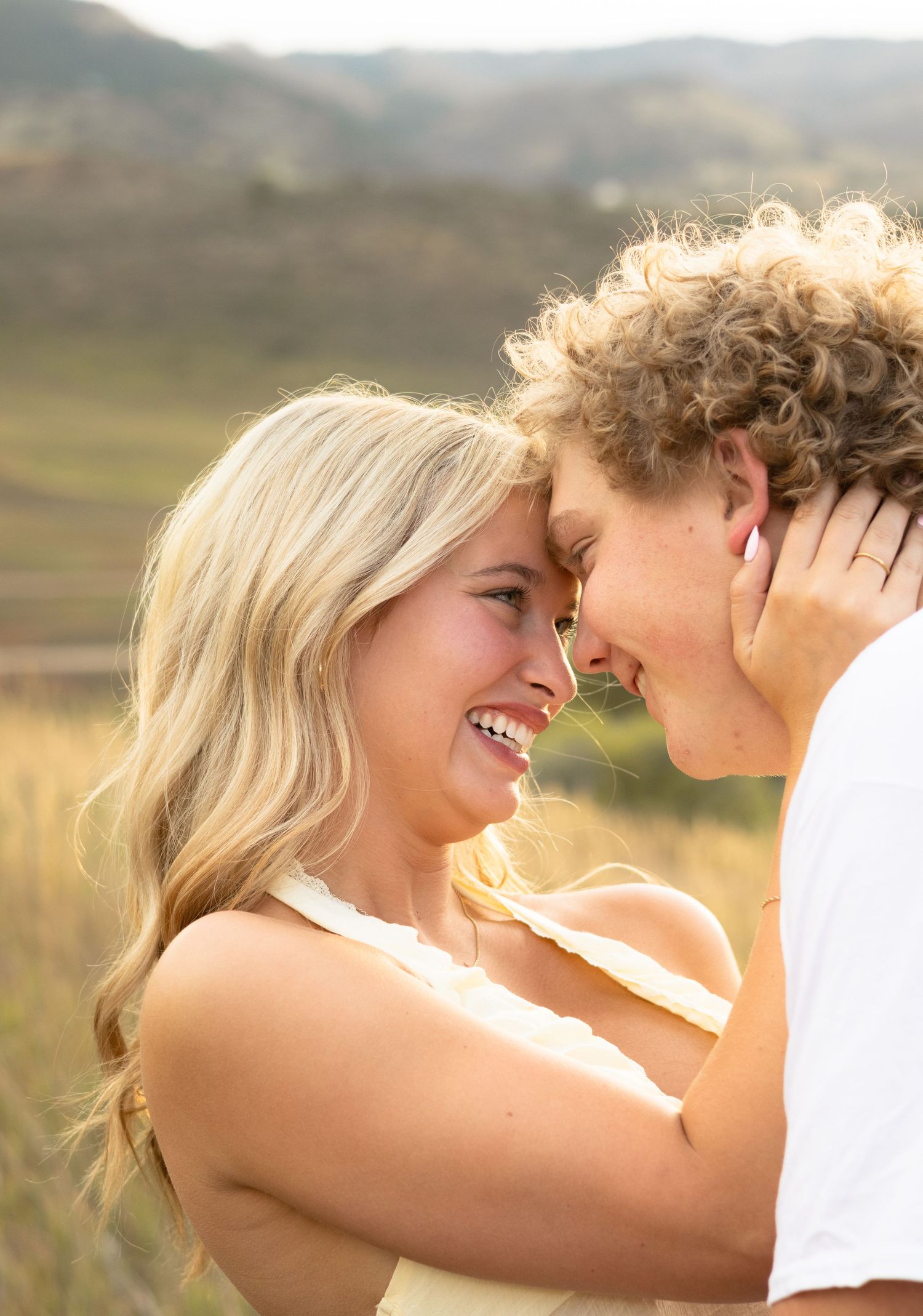 A tender moment between two people in a sunlit field during golden hour.