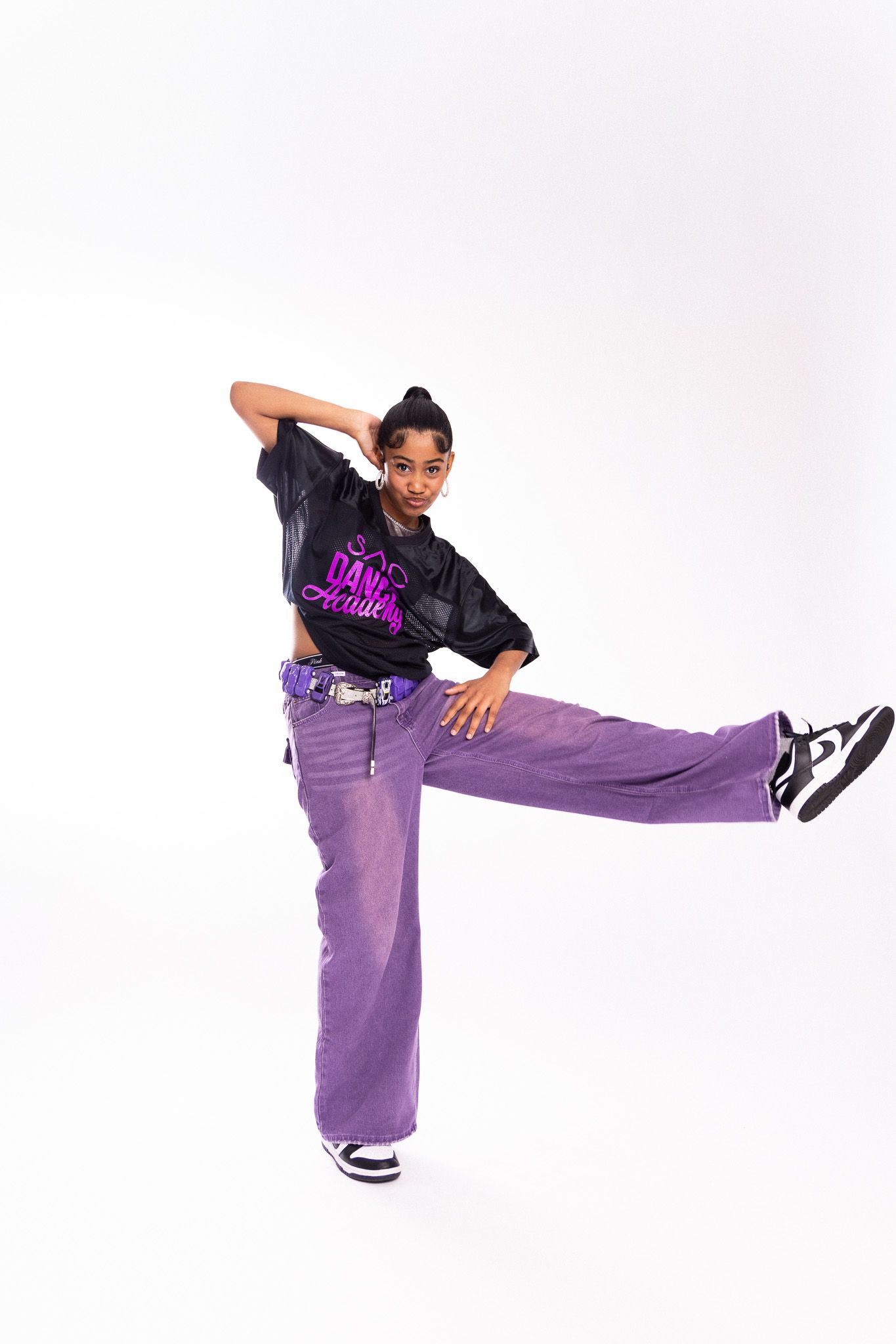 Dancing sequence showing fluid movements in purple pants and black top against white background.