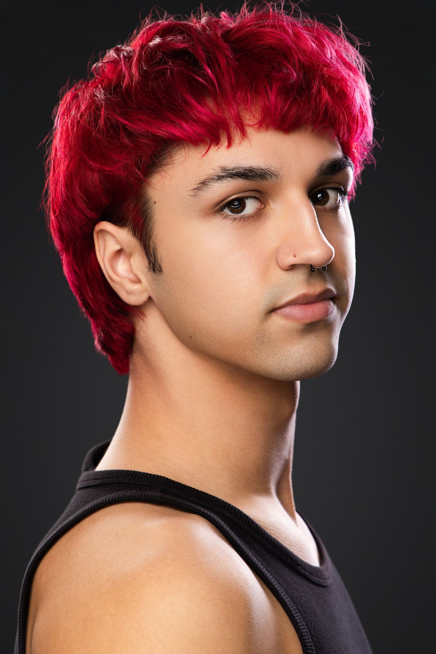 Studio portraits showing different angles of a person with vibrant red hair wearing a black tank top against a dark background.