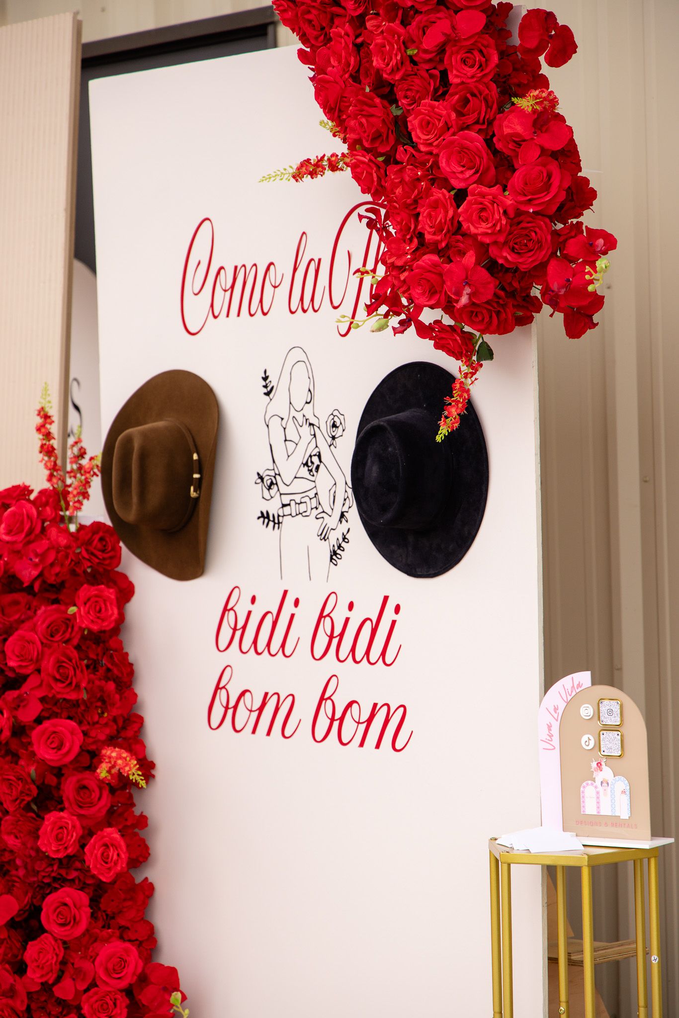 Interior wall decorated with bright red rose garlands and text art against white walls with gold accents.