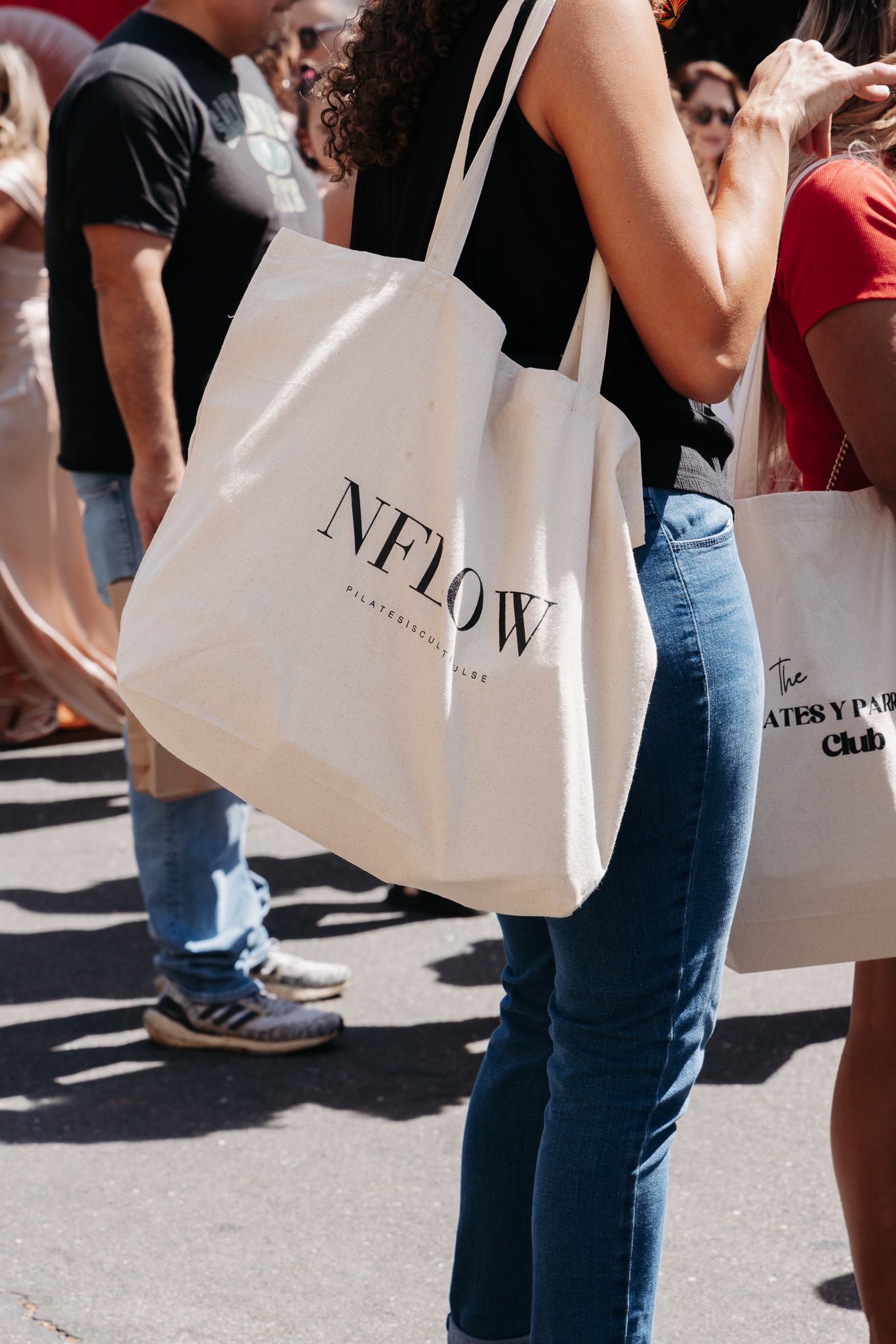 Shoppers carrying white designer shopping bags while walking on a city street.