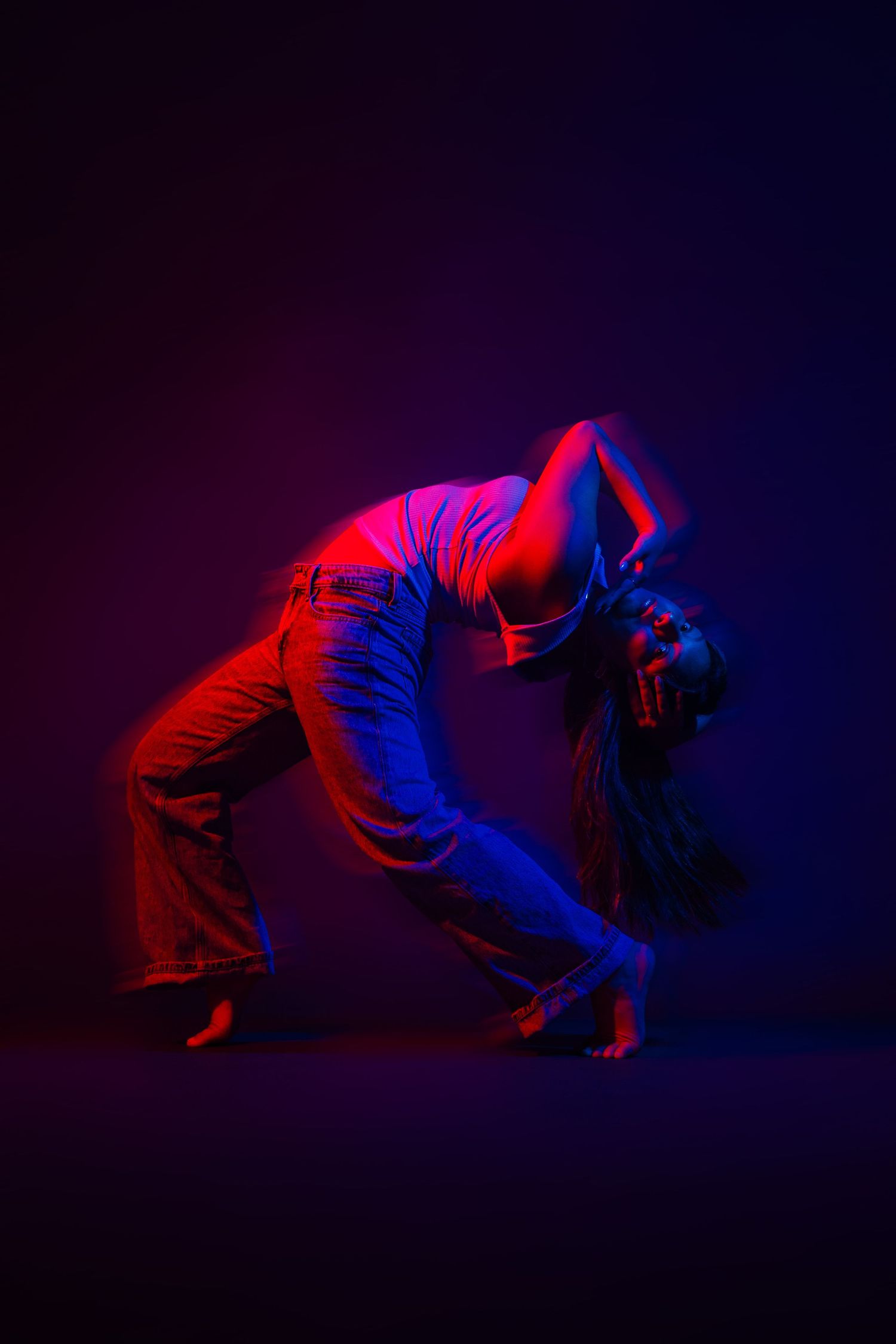 Dynamic breakdance moves illuminated by red and blue lights showing floor-based power moves.