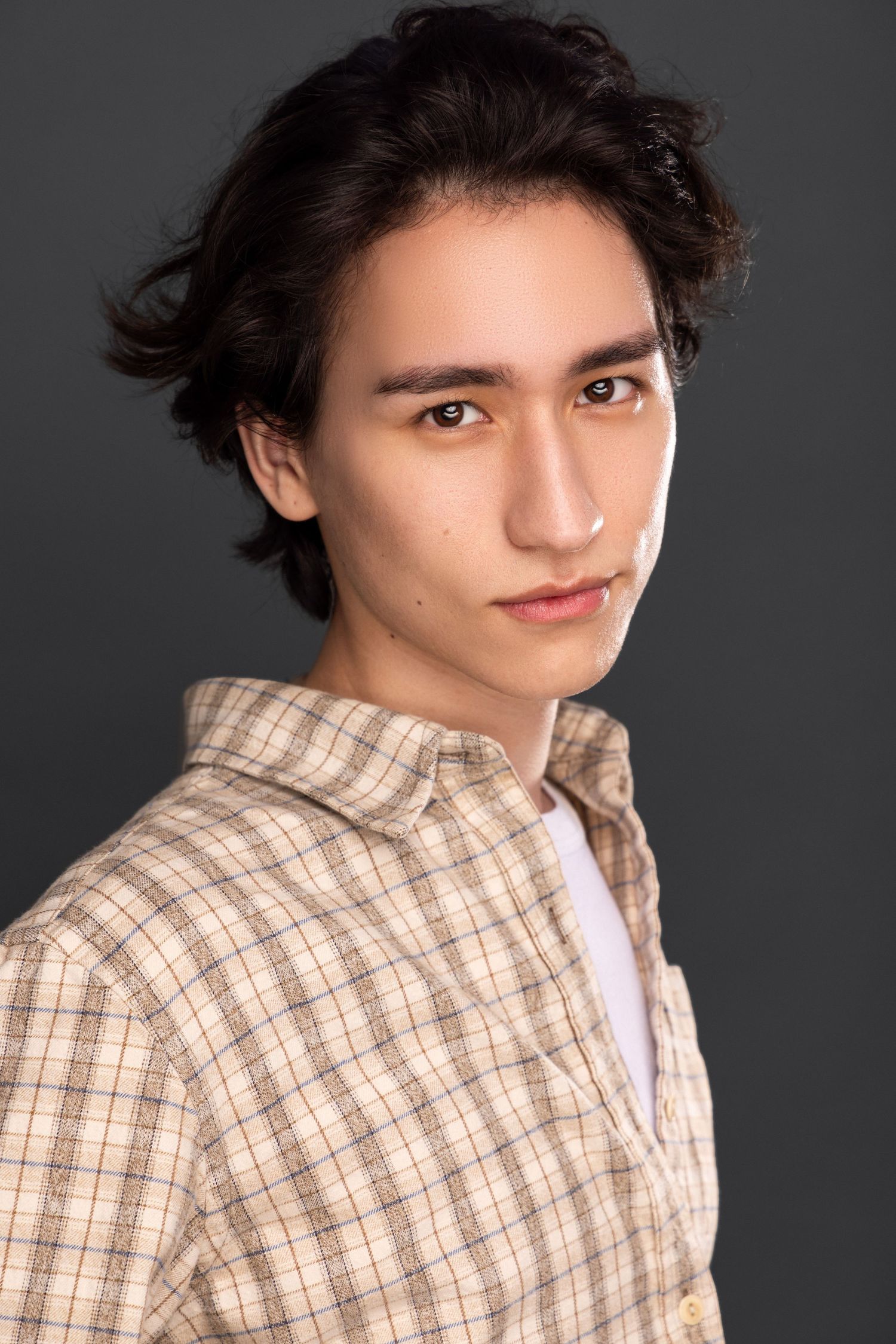 Multiple headshots against dark background wearing plaid button-up shirt.