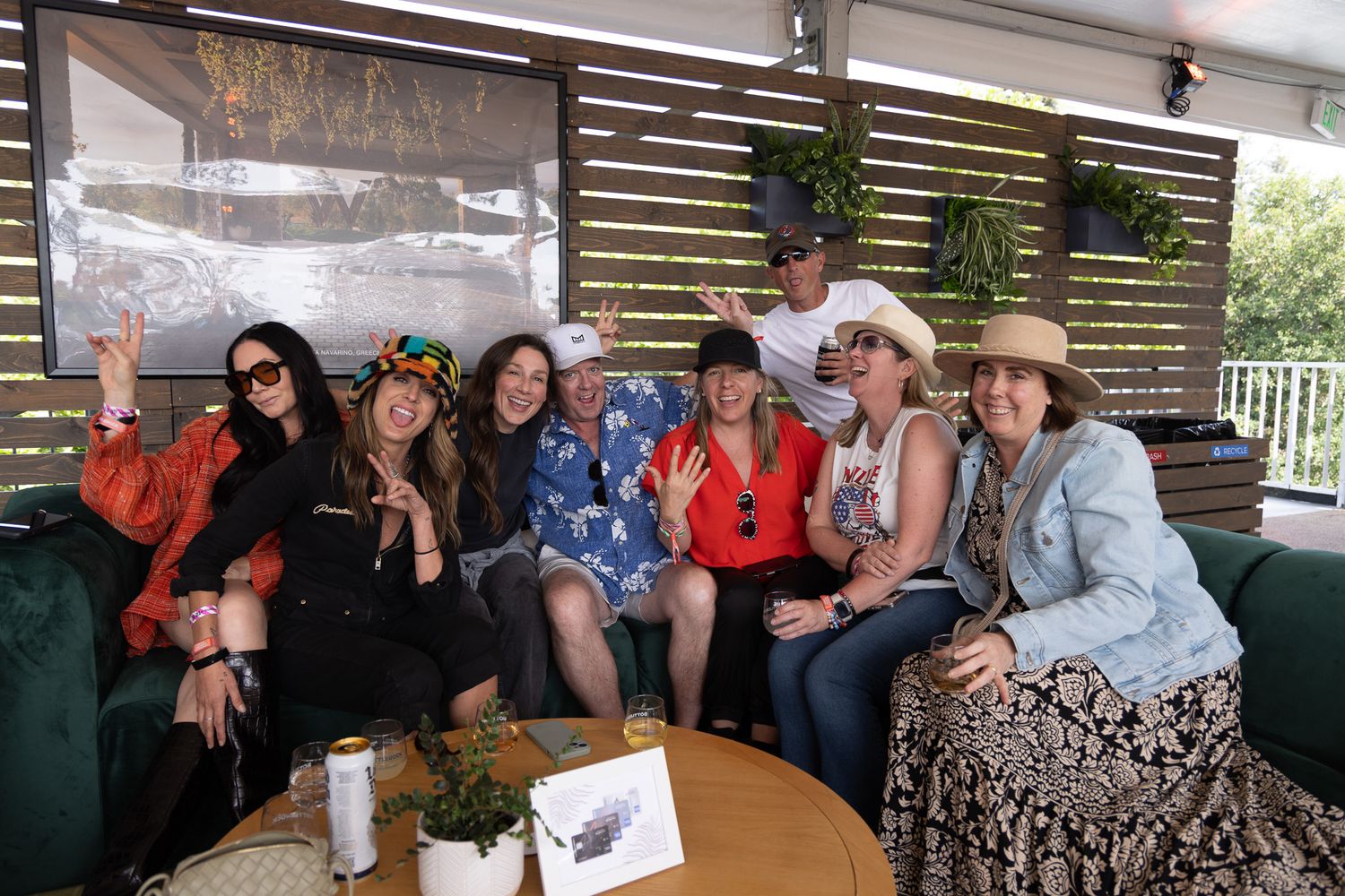 A group of people gathered on outdoor patio furniture during a social event at a covered deck area.