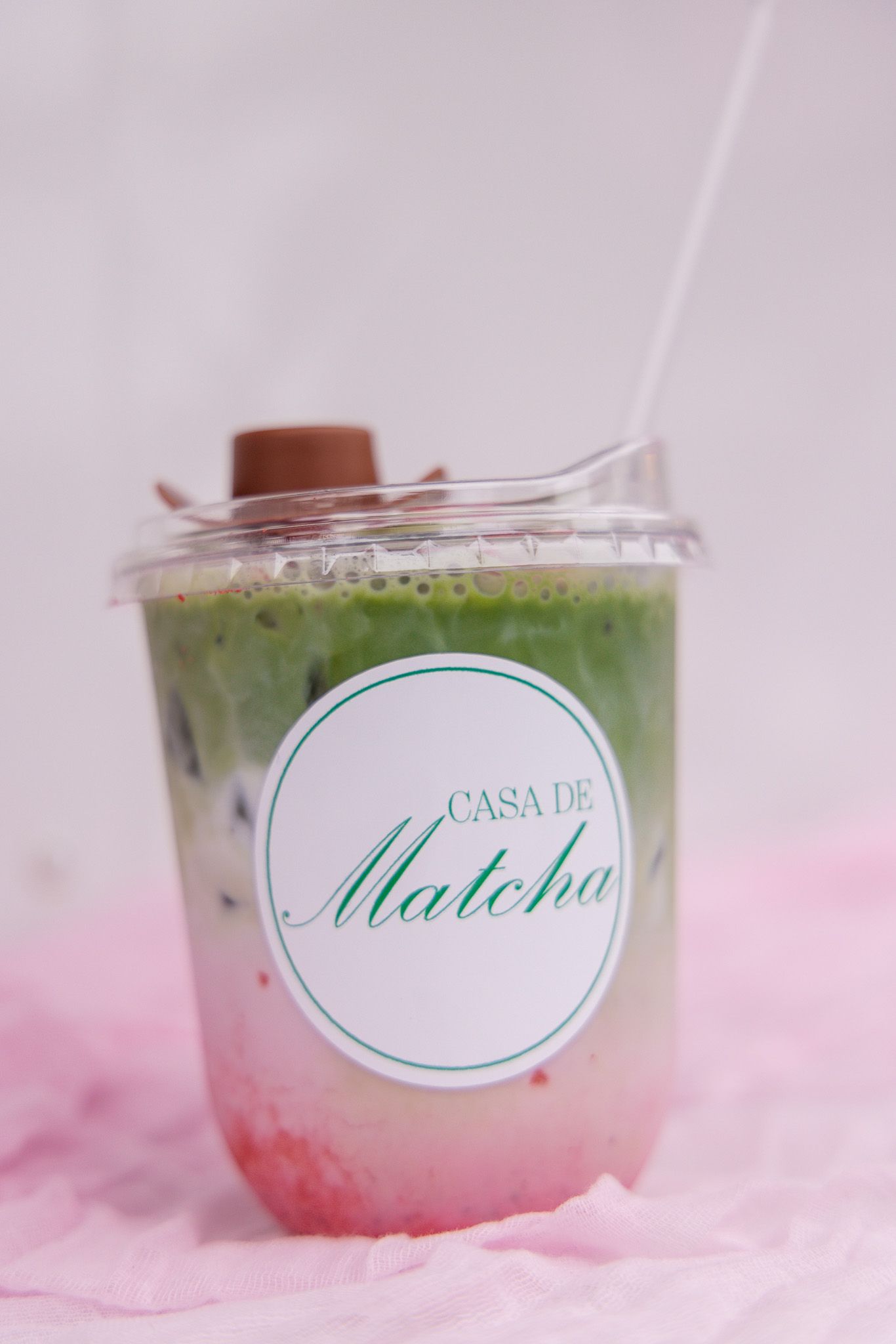 Gradient colored matcha drink with pink and green layers in clear cups against a soft pink background.