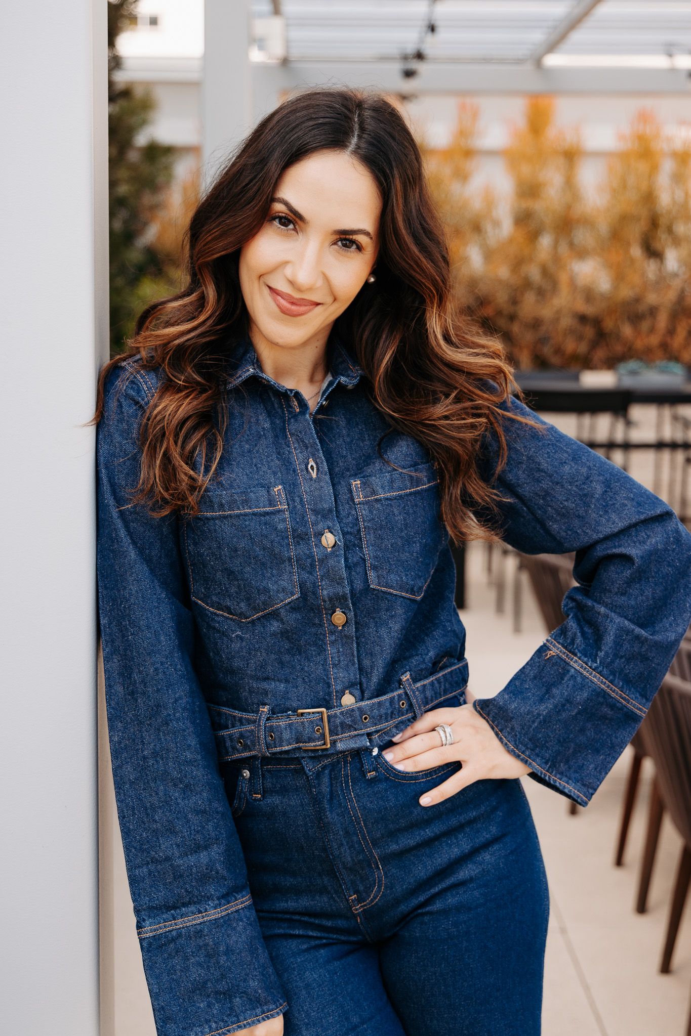 Fashionable denim jumpsuit shown in multiple poses against a light-colored outdoor setting.