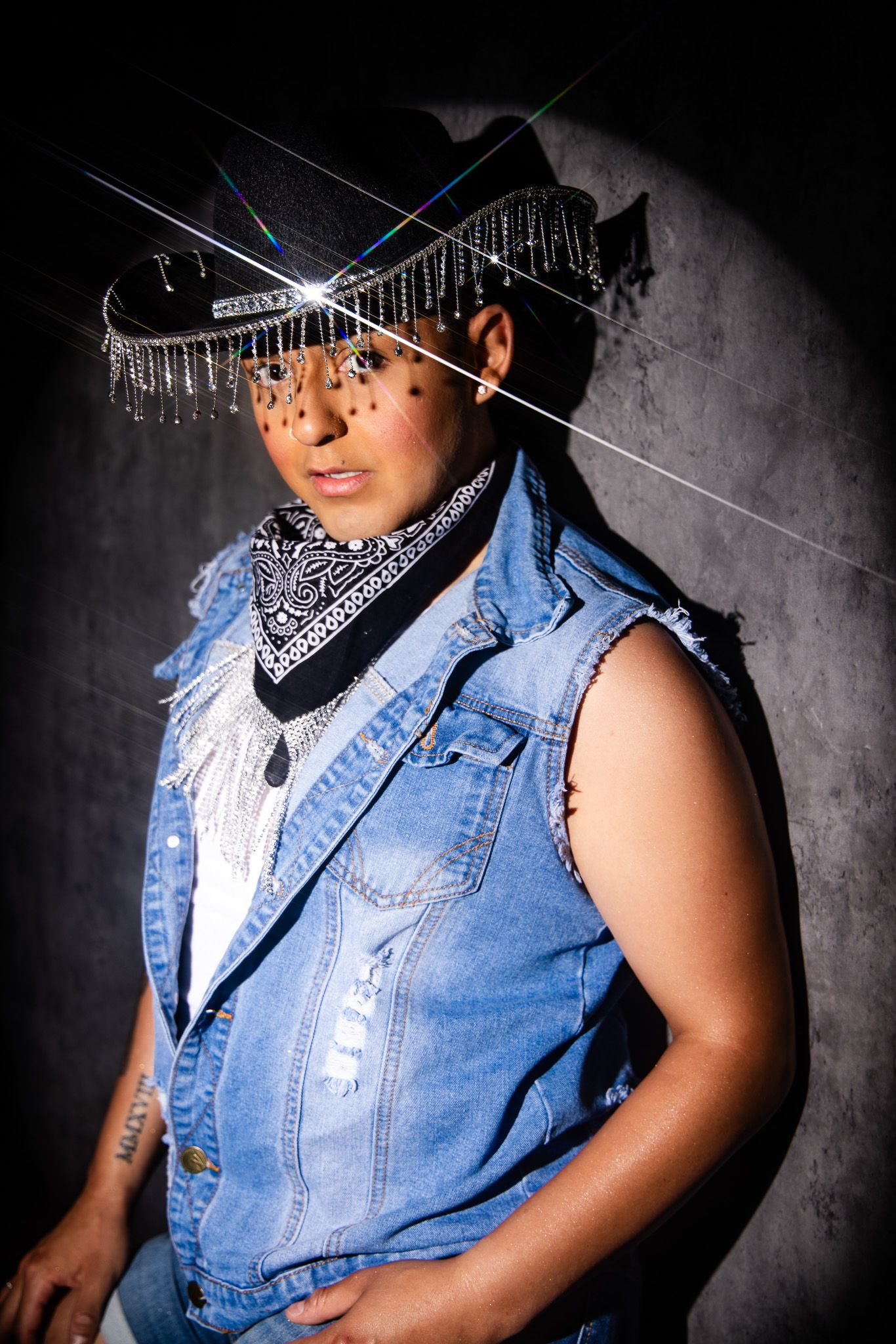 A person wearing a sleeveless denim vest, baseball cap, and bandana poses against a dark background in multiple angles.
