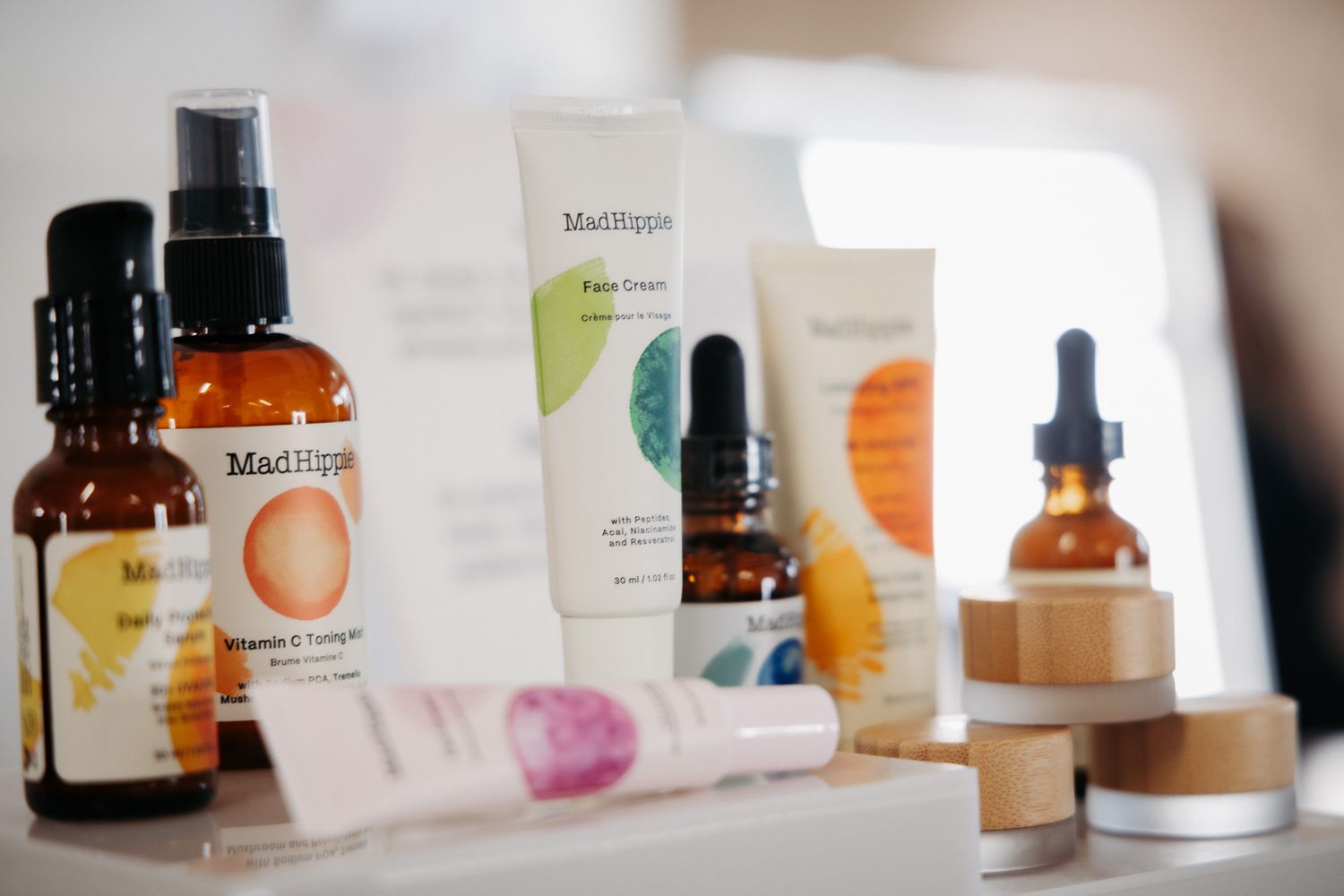 Various skincare and beauty product bottles lined up against a light background with colorful watercolor accents.