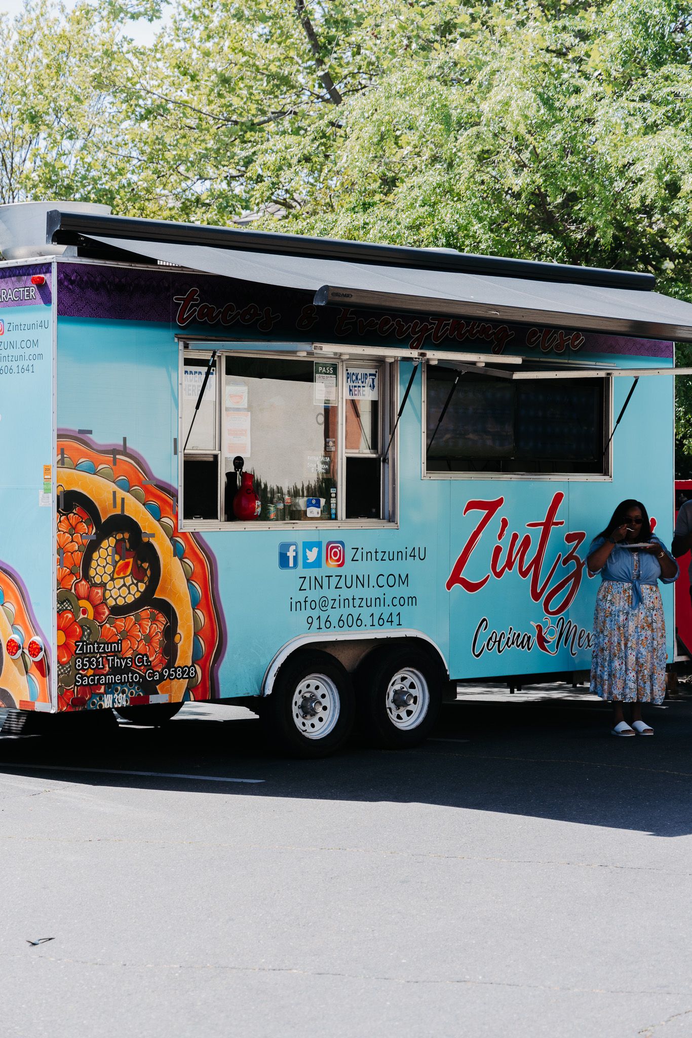 A colorful food truck painted in light blue with decorative artwork and graphics displayed along its exterior.