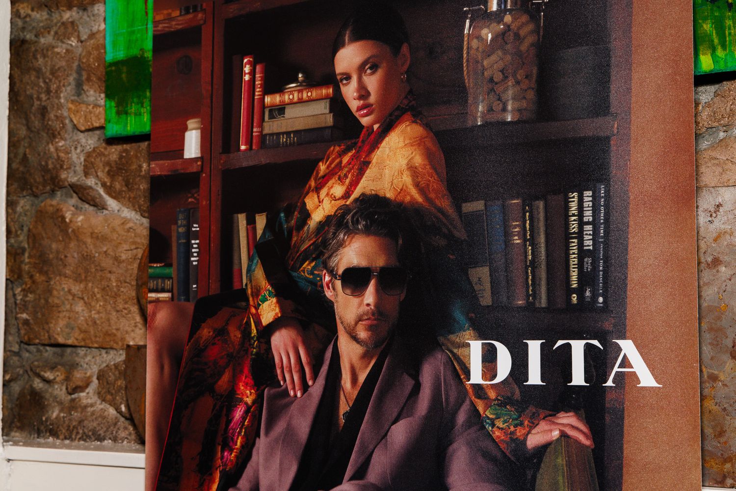 DITA eyewear advertisement featuring two models in luxurious attire posing in front of a bookshelf.