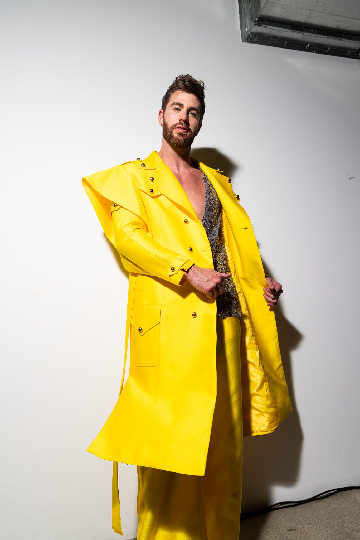 Person wearing bright yellow raincoat strikes dynamic poses against white background in fashion photo series.