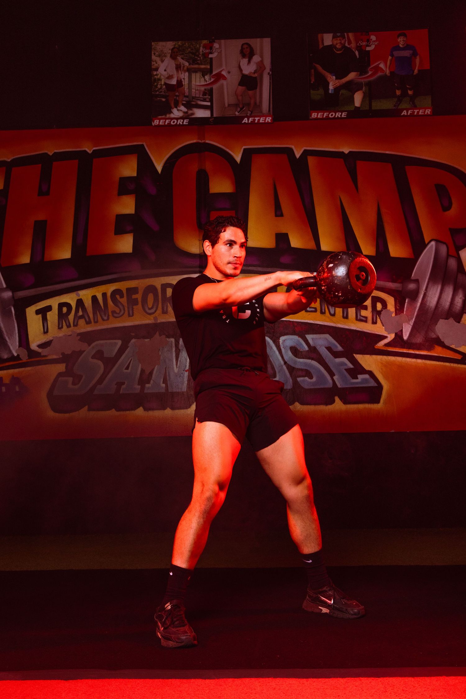 Person in athletic gear performing a squat exercise in a dimly lit red fitness studio.