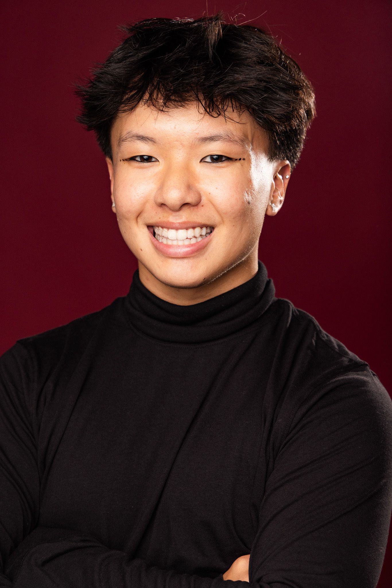 A series of four headshots showing someone in a black turtleneck sweater against a burgundy background.