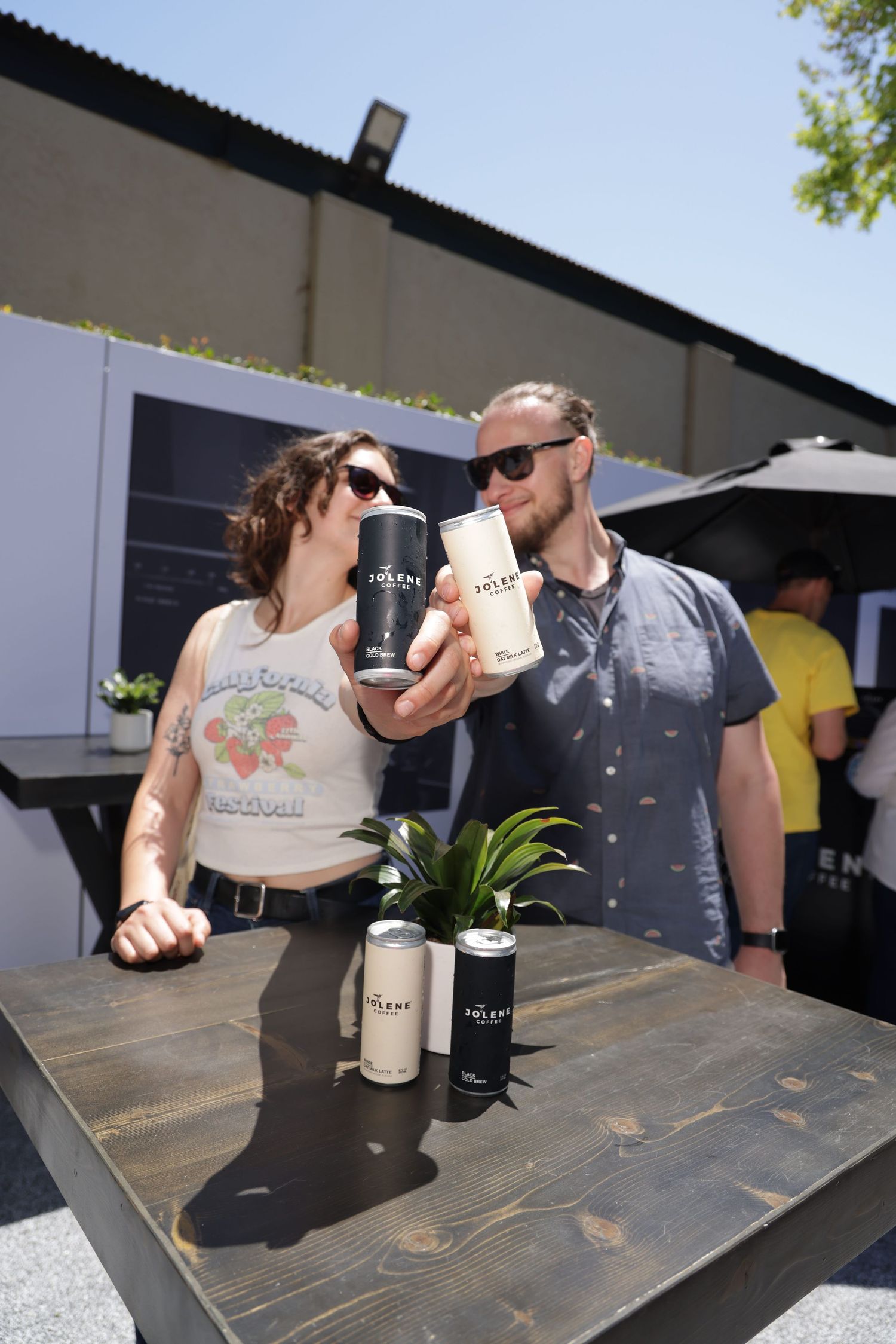 People enjoying drinks at an outdoor table with coffee cups and beverages on a rustic wooden surface.