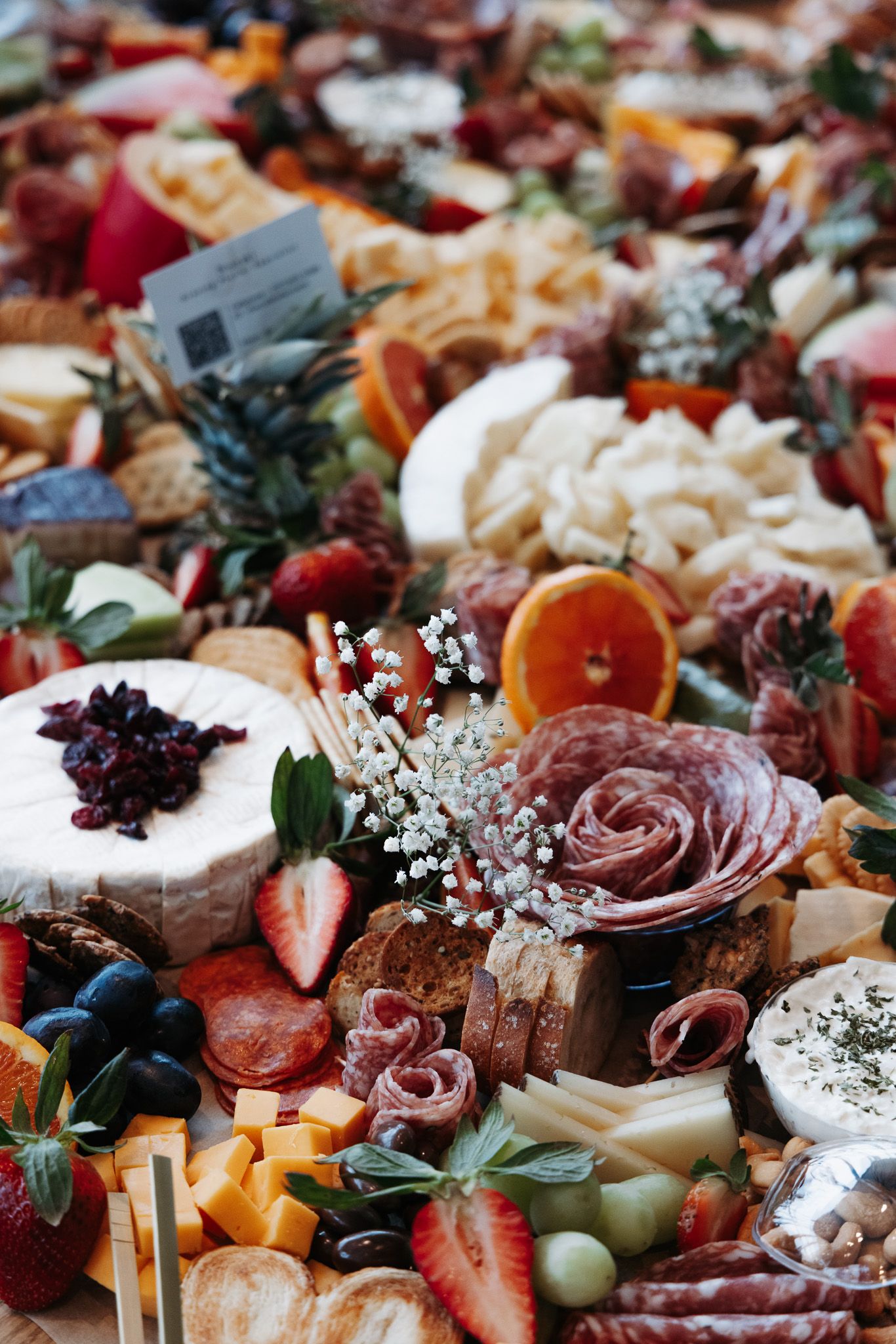 Gourmet charcuterie board with meats, cheeses, fruits, and garnishes artfully arranged on a rustic surface.