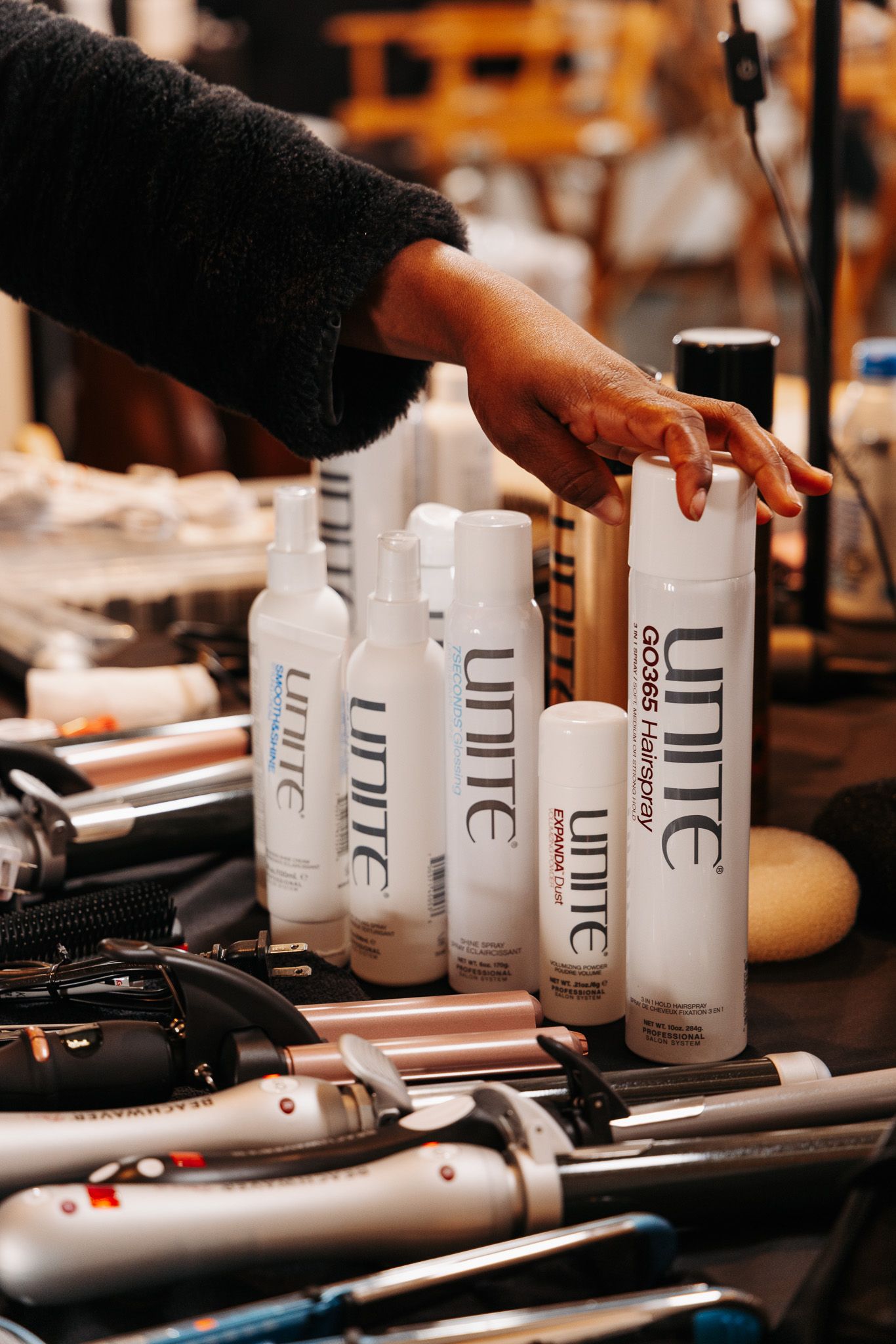 Professional hair styling products and tools arranged on a wooden surface in a salon setting.