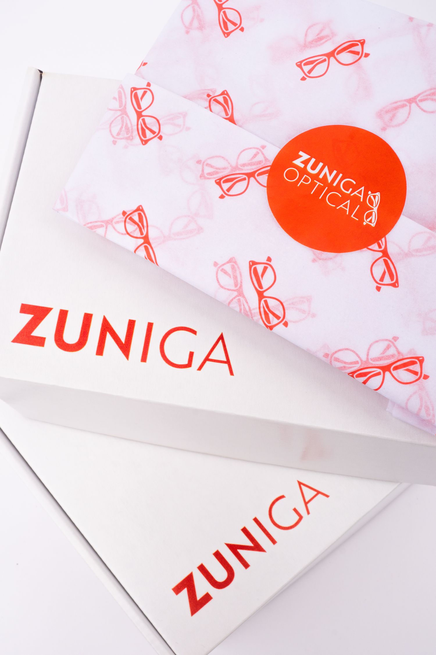 Minimalist white paper branding materials with red Zuniga optical logo design and text elements.
