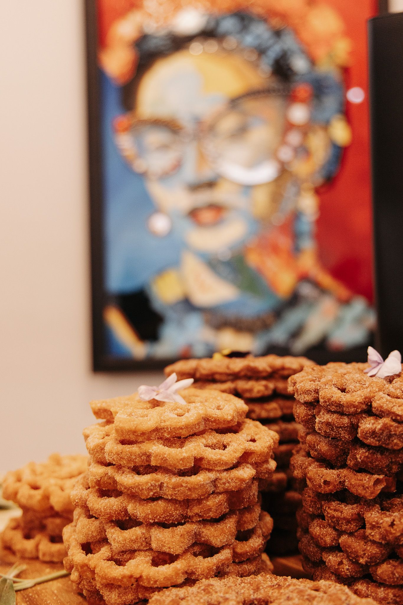 Stacks of golden brown cookies on display with colorful artwork visible in the background.