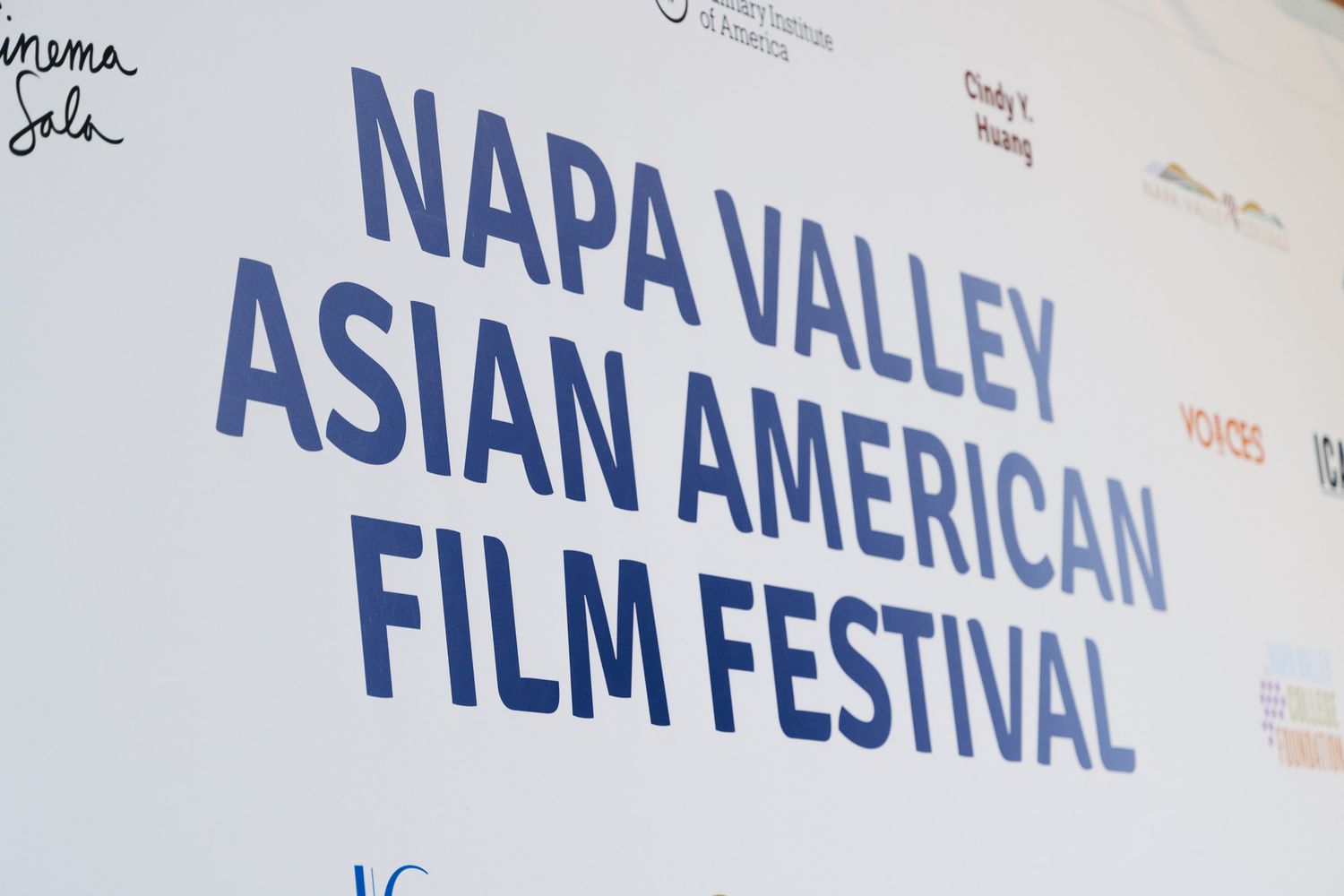 Large blue text signage for Napa Valley Asian American Film Festival mounted on white wall.