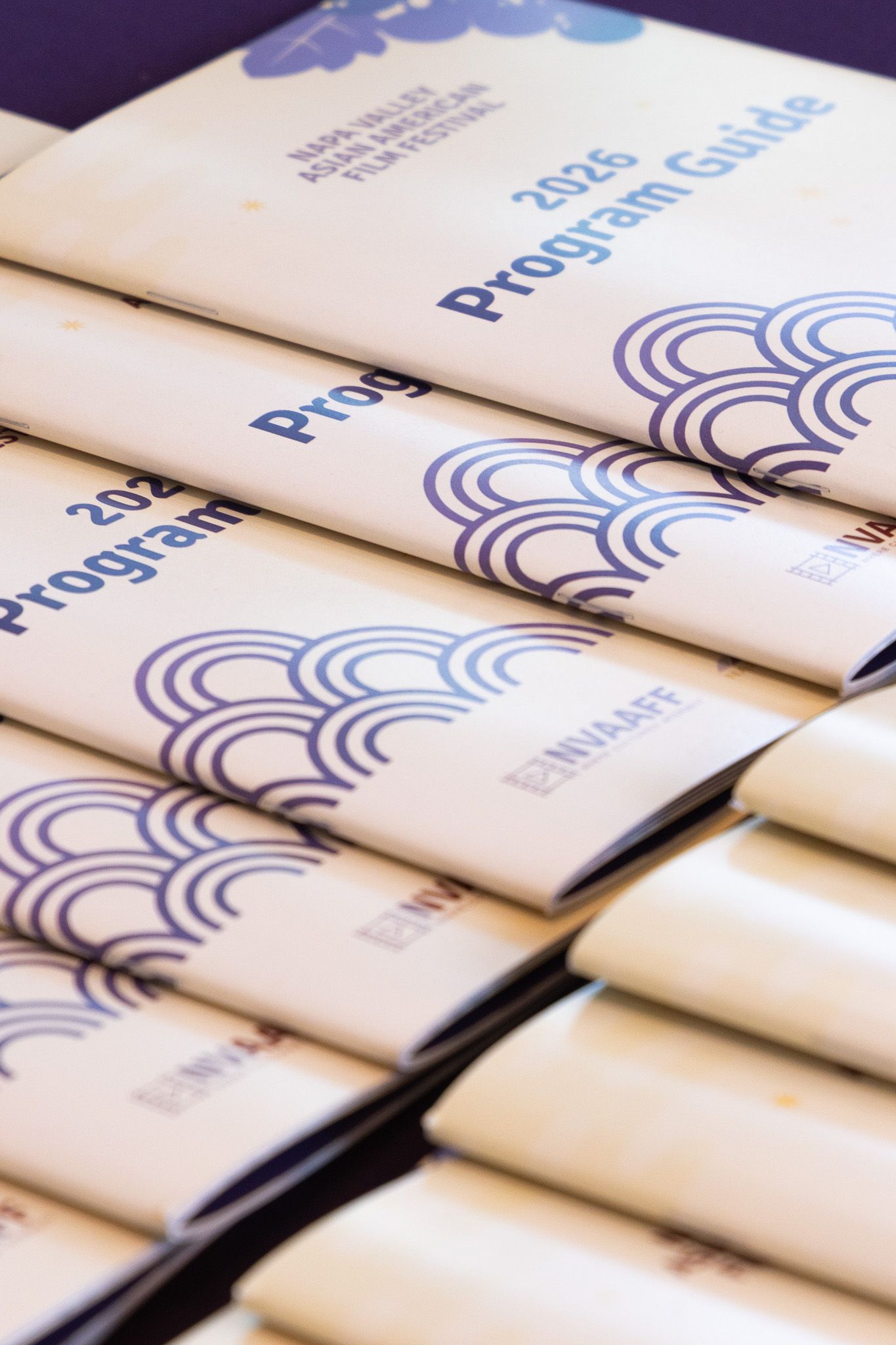 Row of printed event programs with blue wave designs displayed in overlapping arrangement.