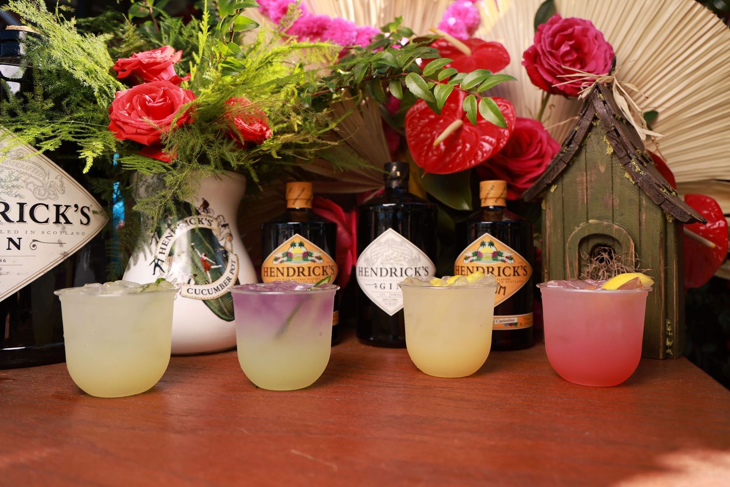 Colorful floral arrangements with pink and red roses displayed alongside decorative paper fans on a wooden surface.
