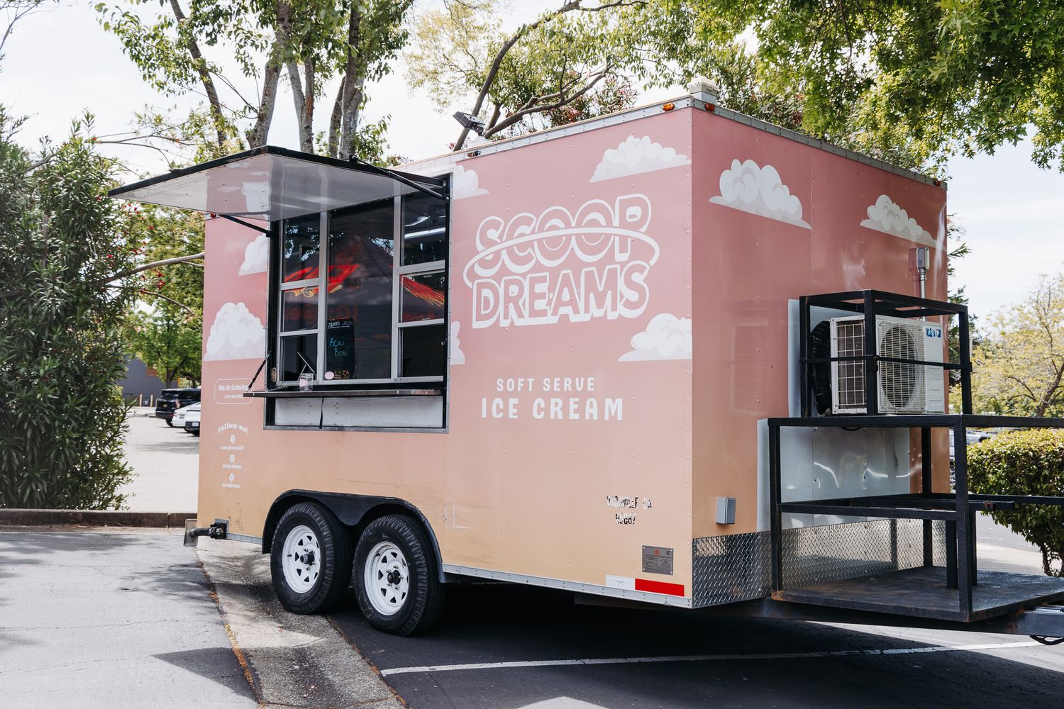 Pink Scoop Dreams soft serve ice cream food trailer parked outdoors, featuring vintage-style signage and serving window.
