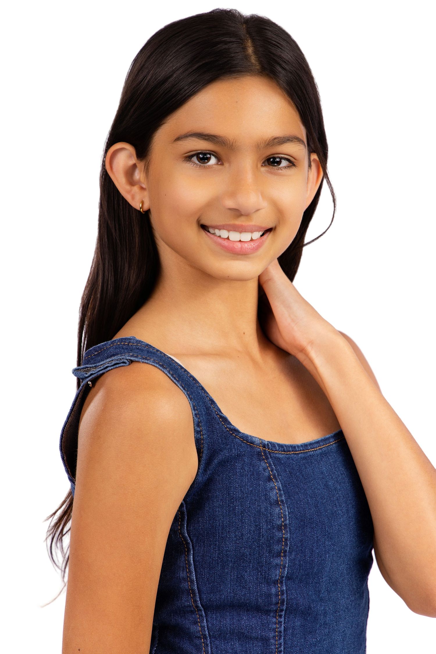 Person in denim sleeveless top smiling while posing against white background with long dark hair.