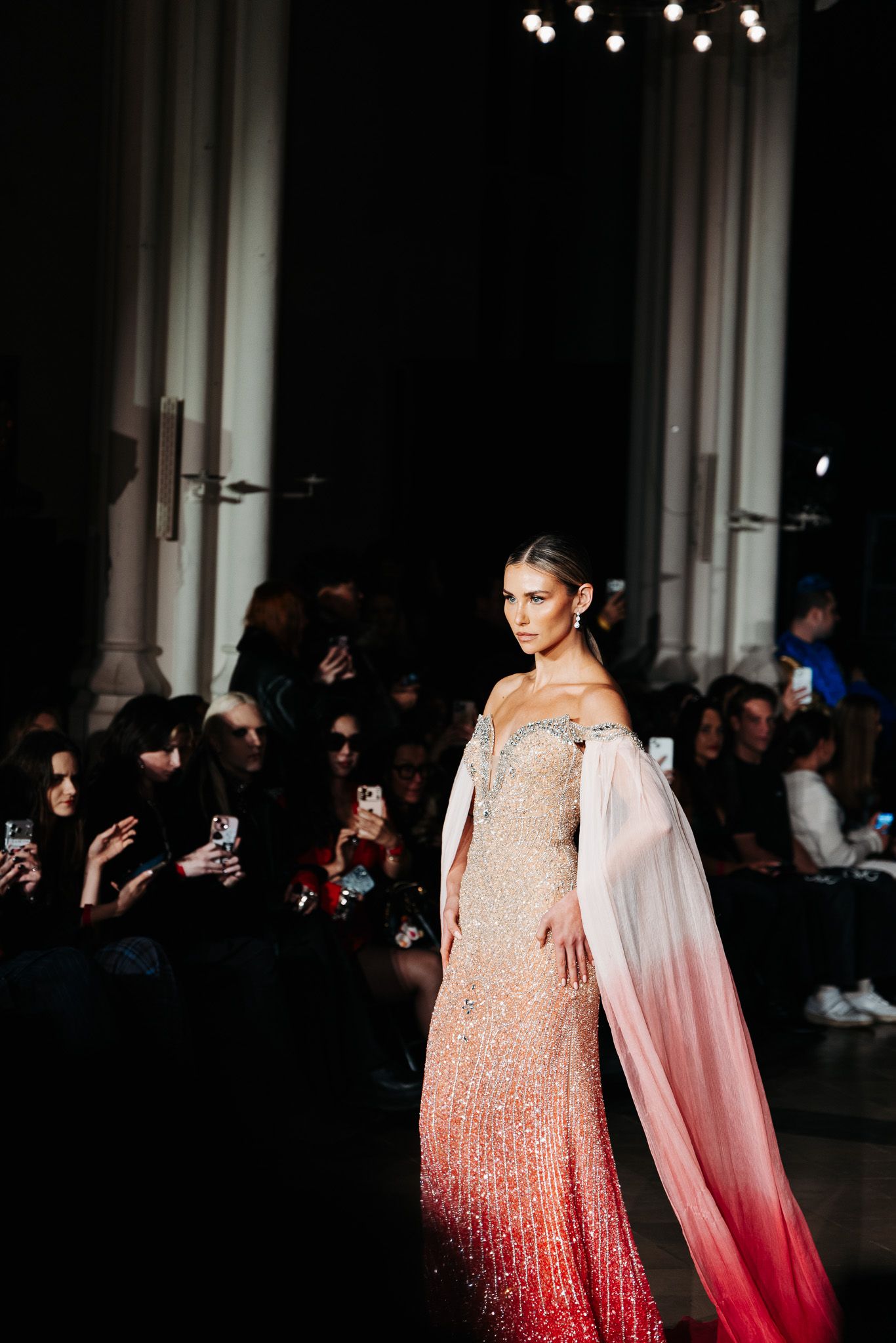 Fashion show presents ombre gown transitioning from white to red with dramatic cape detail.
