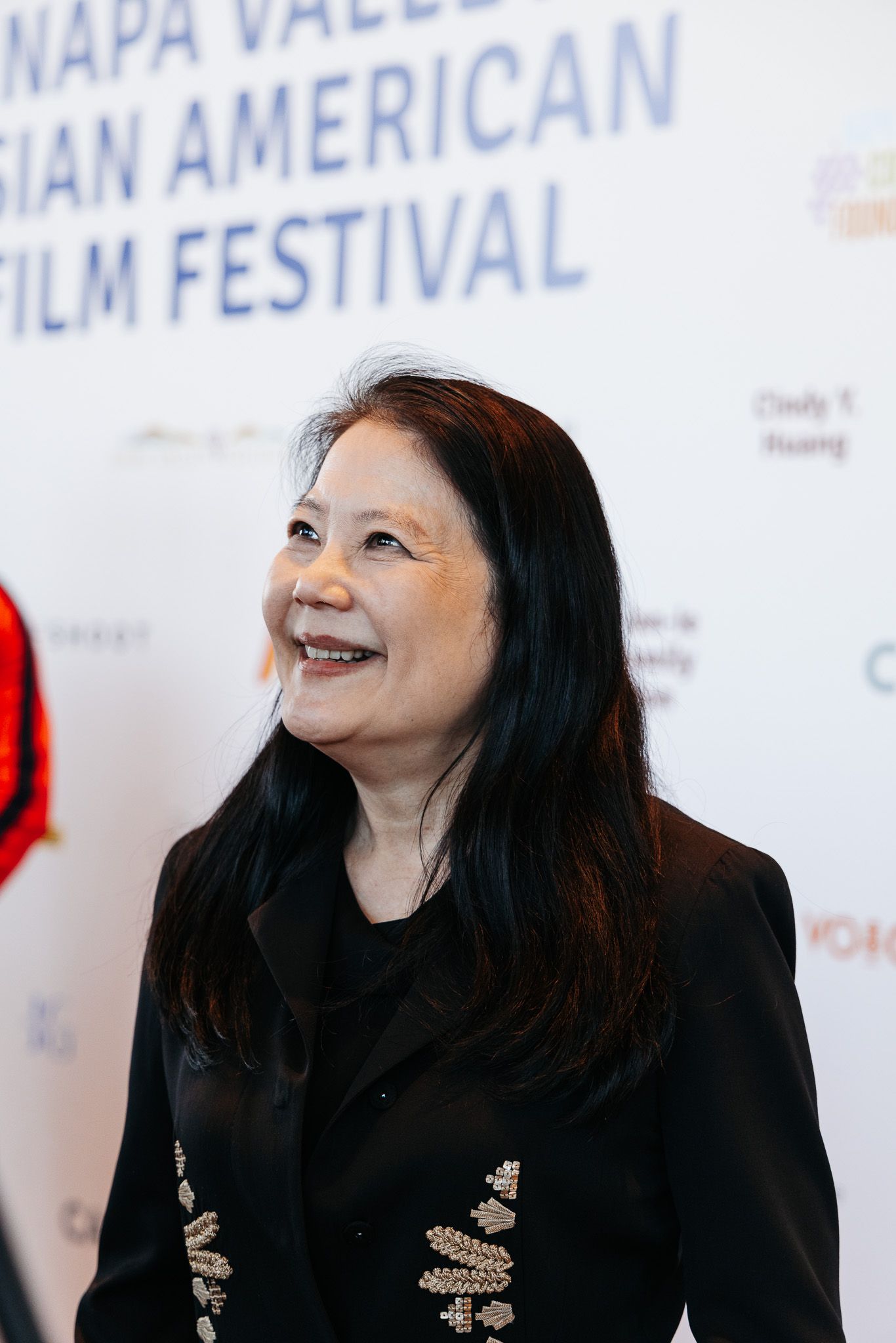 Film festival backdrop with attendee in black attire looking to the side.