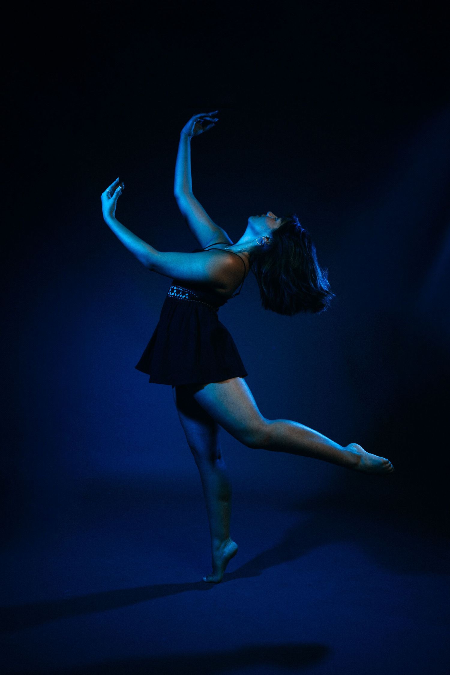 Silhouetted dancer leaps and twirls through moody blue lighting.