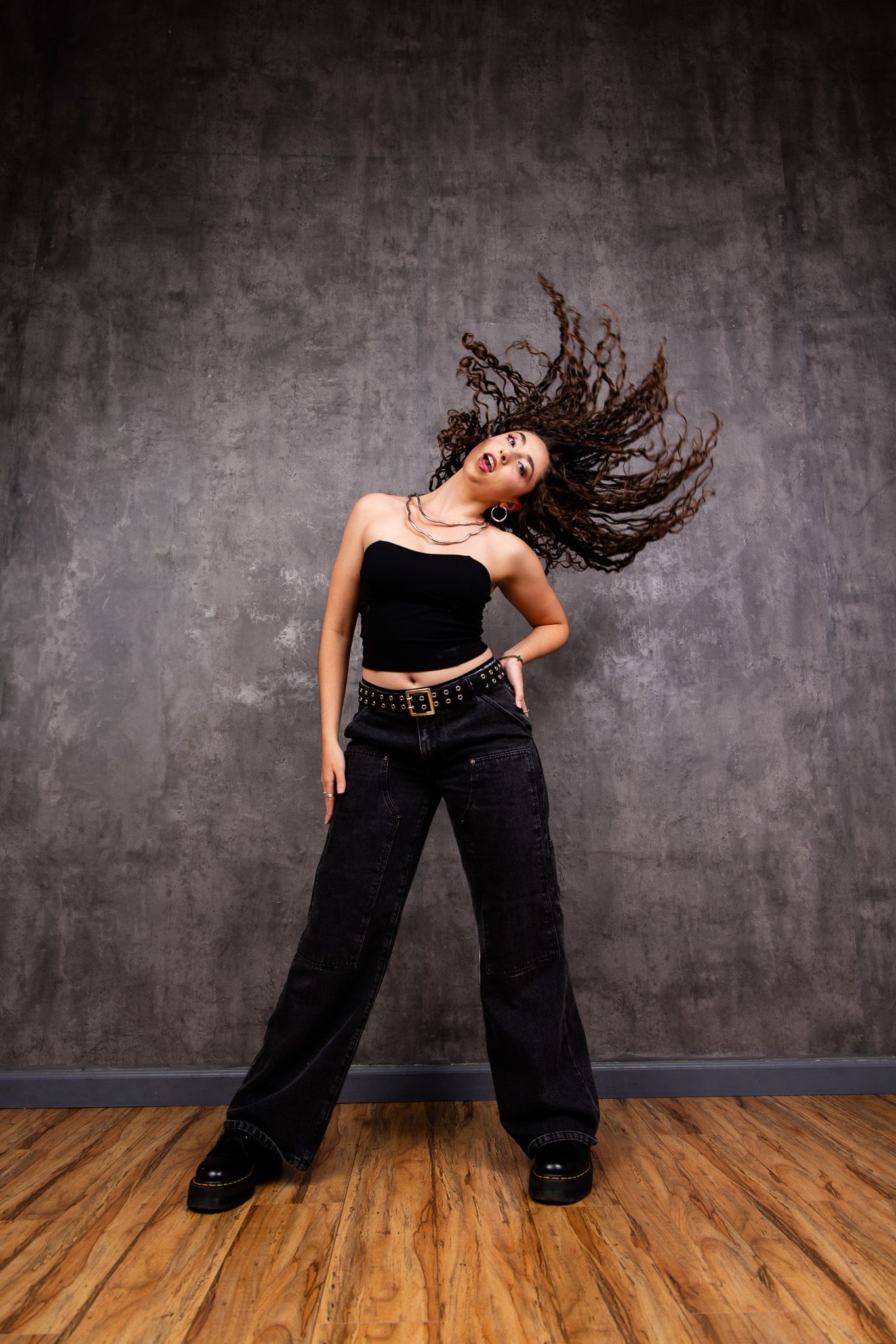 Dynamic dance sequence showing expressive movements against a textured gray wall and wooden floor.
