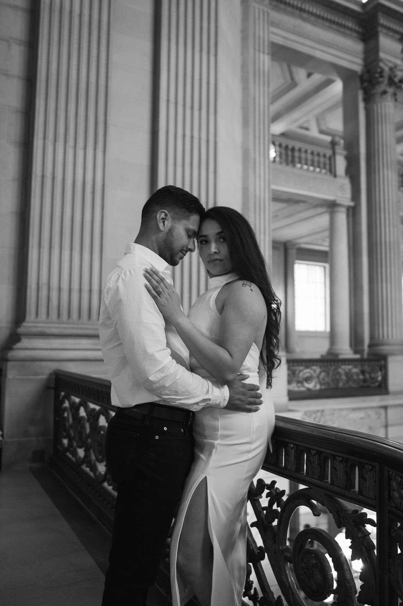 A romantic black and white photo series showing a couple embracing and dancing in an elegant hallway with columns.