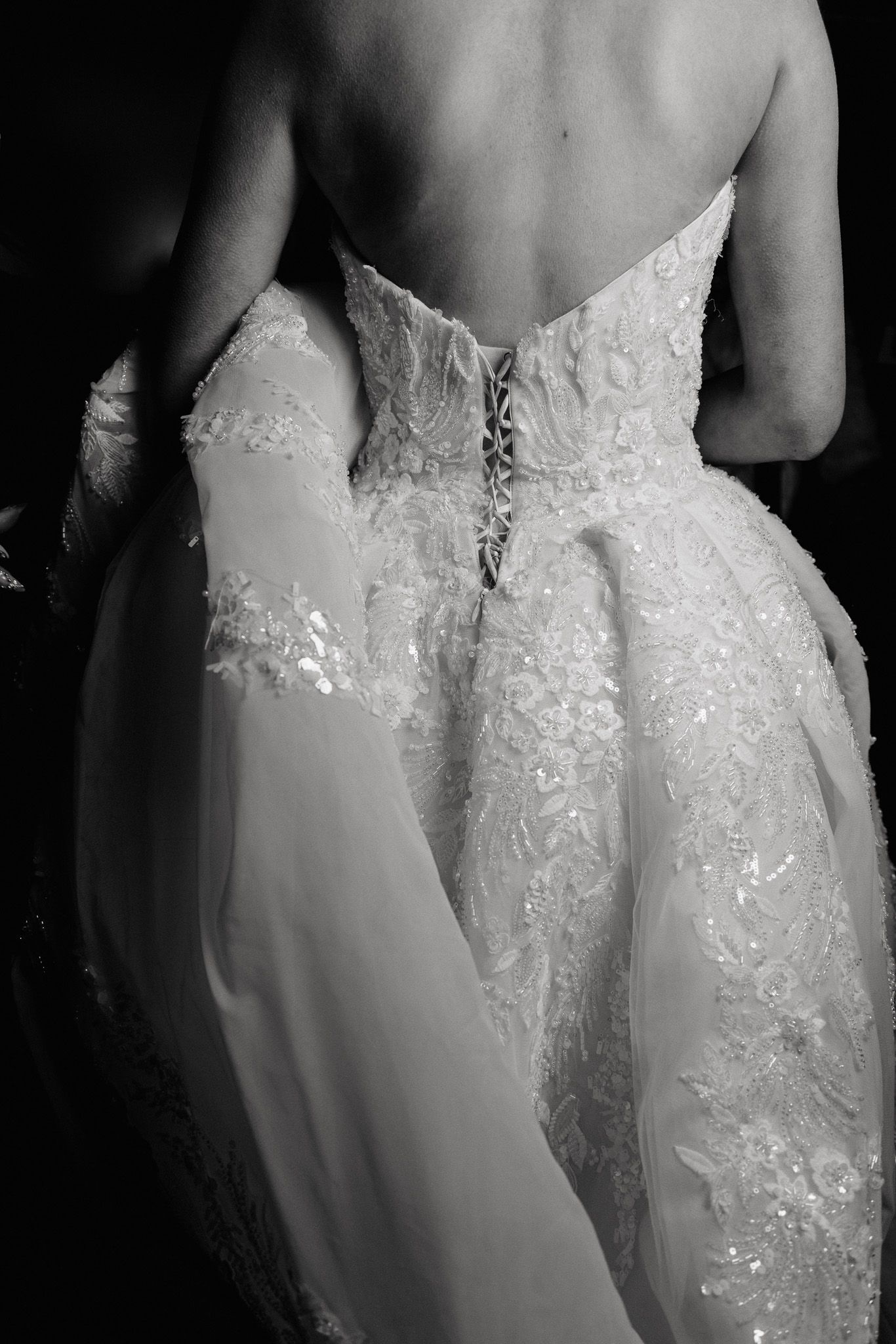 Close-up details of a white lace wedding dress with sequins and beading.