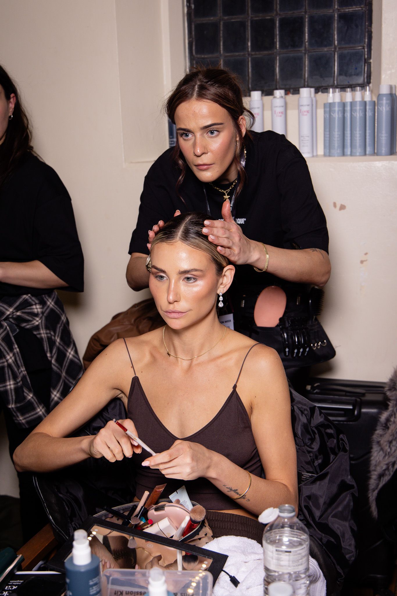 Behind-the-scenes makeup preparation showing styling team at work.