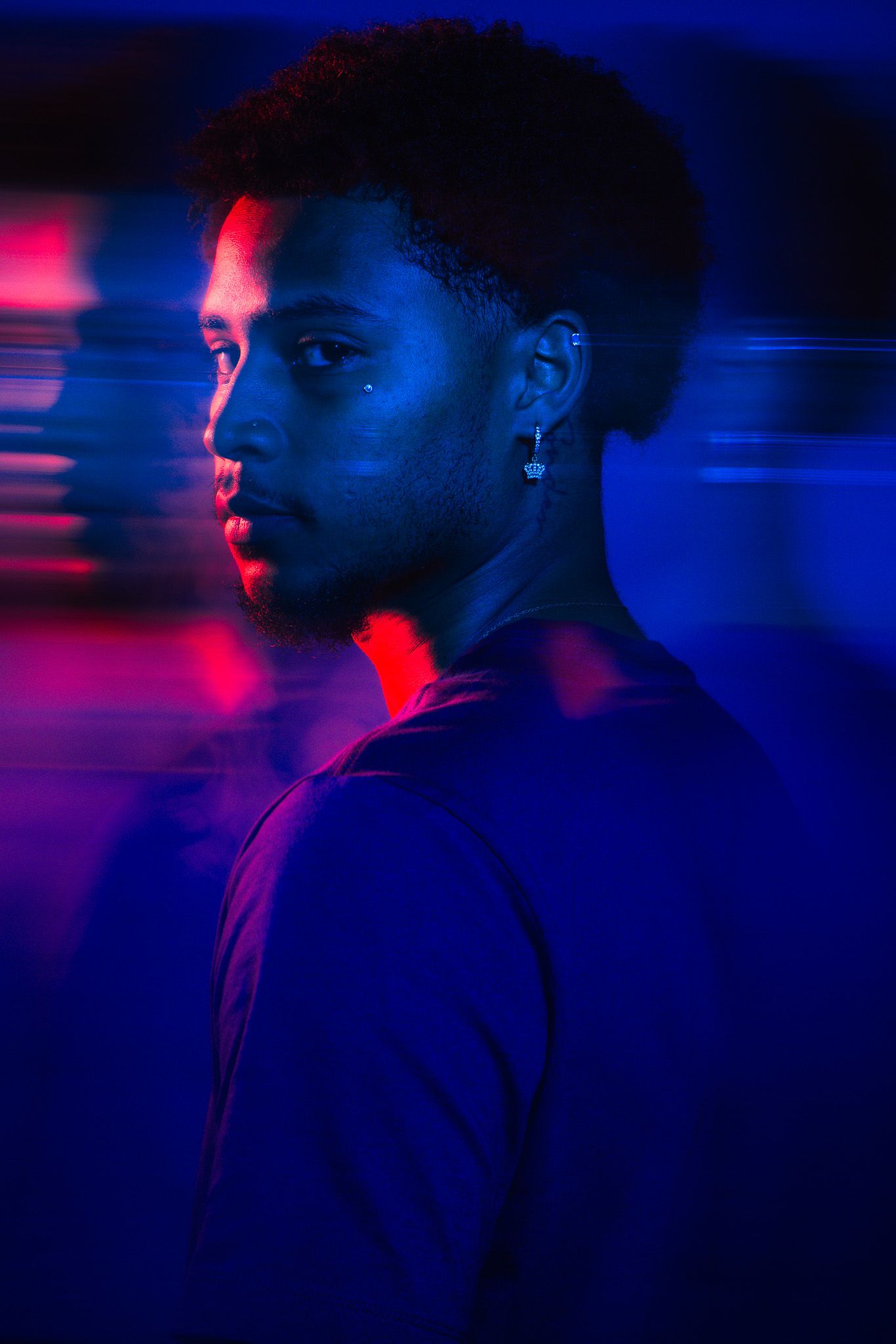 Young man portrait with dramatic blue and red neon lighting creating a double exposure effect.