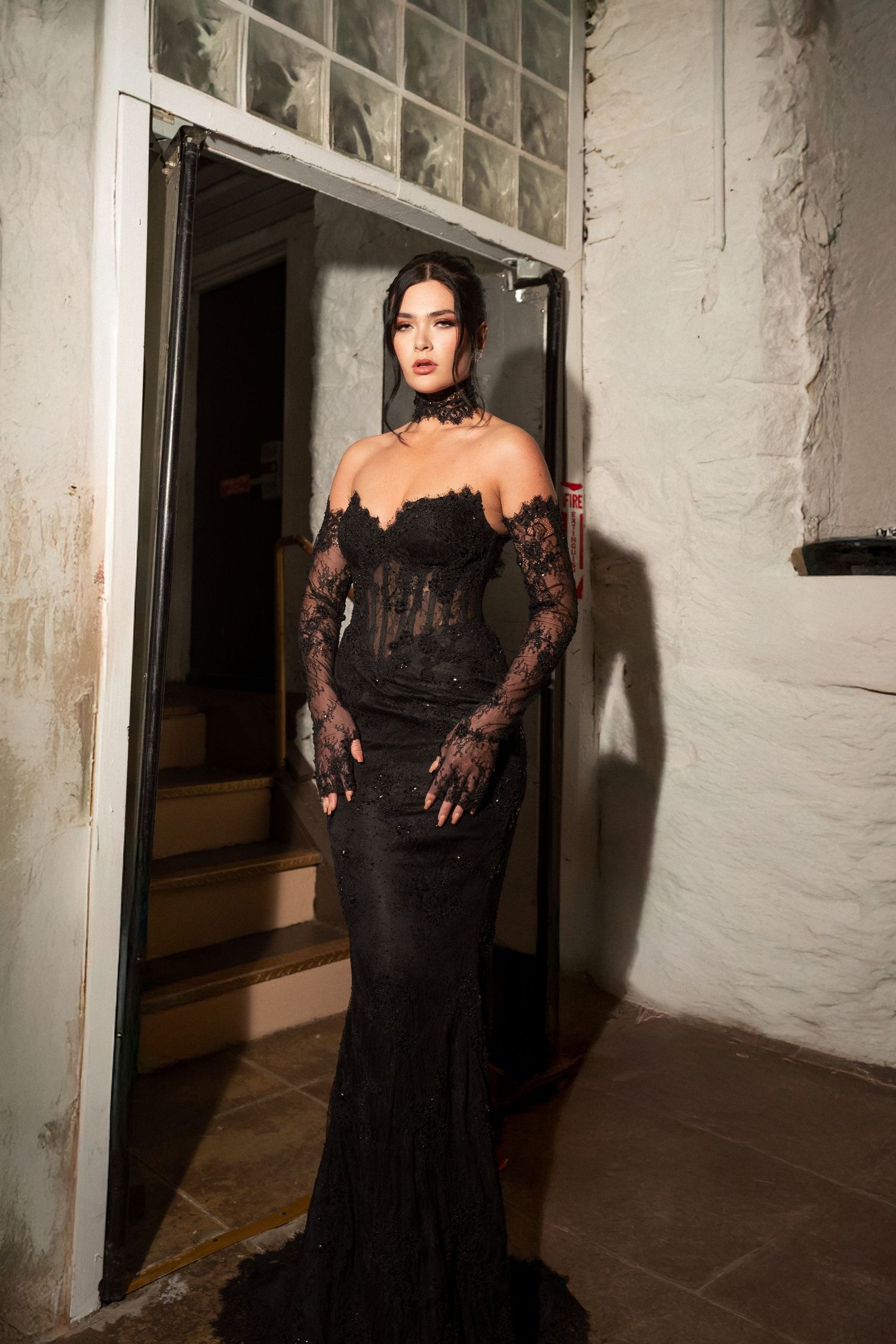 A dramatic fashion photo series showing a figure in a flowing black lace gown posed in a white corridor.