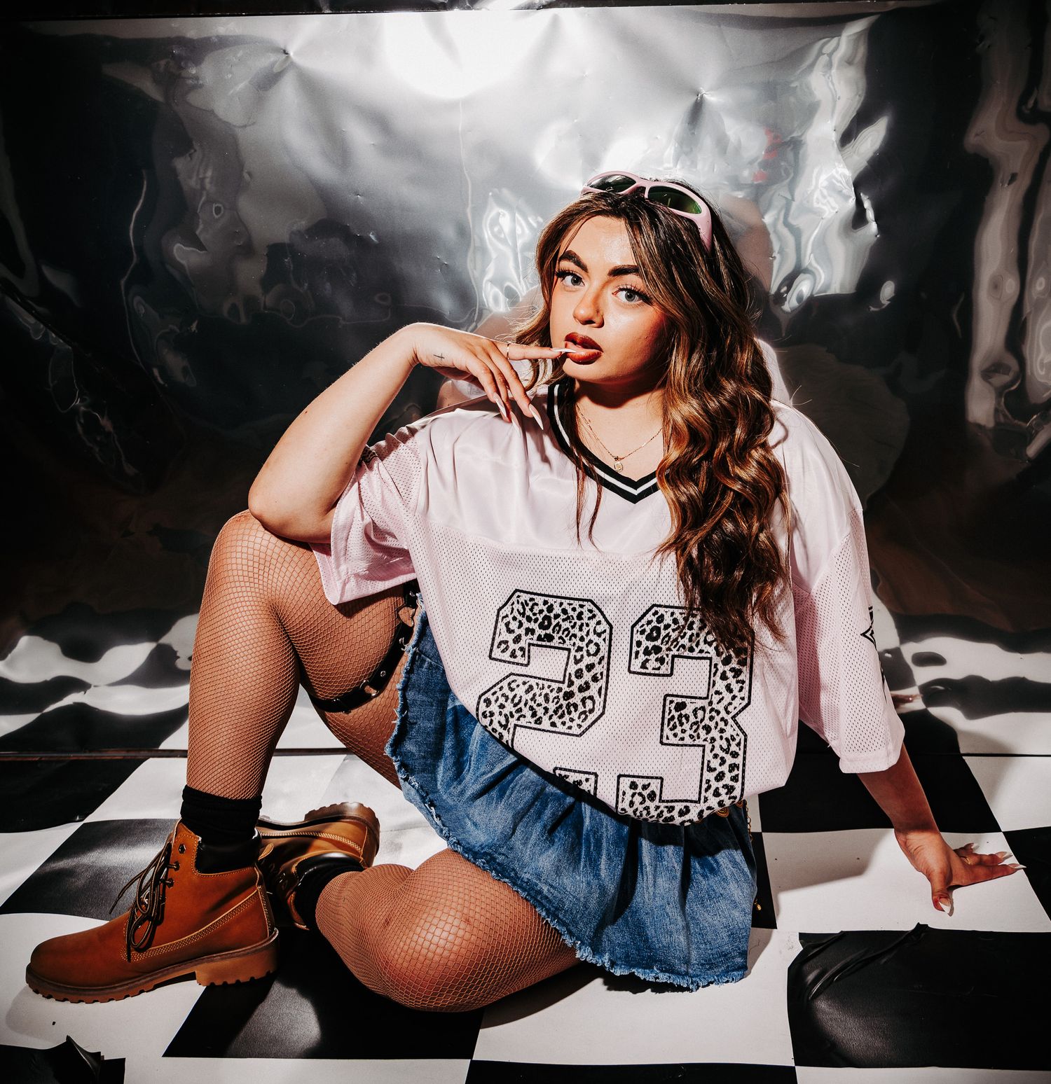 Figure in white t-shirt with graphic print and denim shorts poses on floor with dramatic lighting and smoke effects.