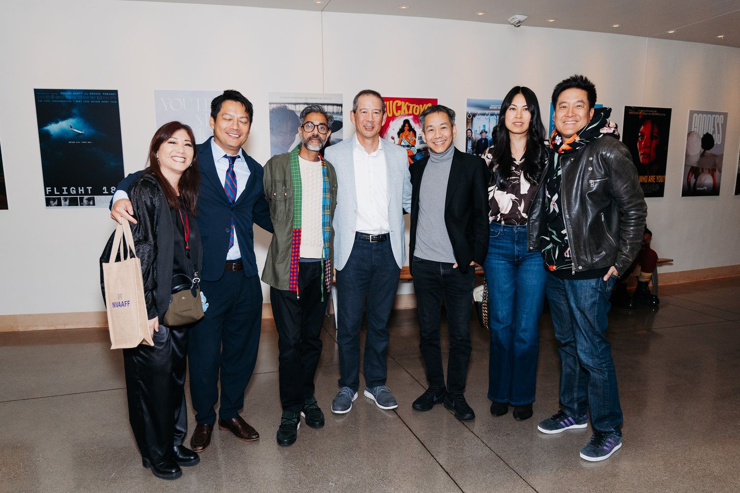 Group photo of festival attendees standing together against a wall with framed artwork.