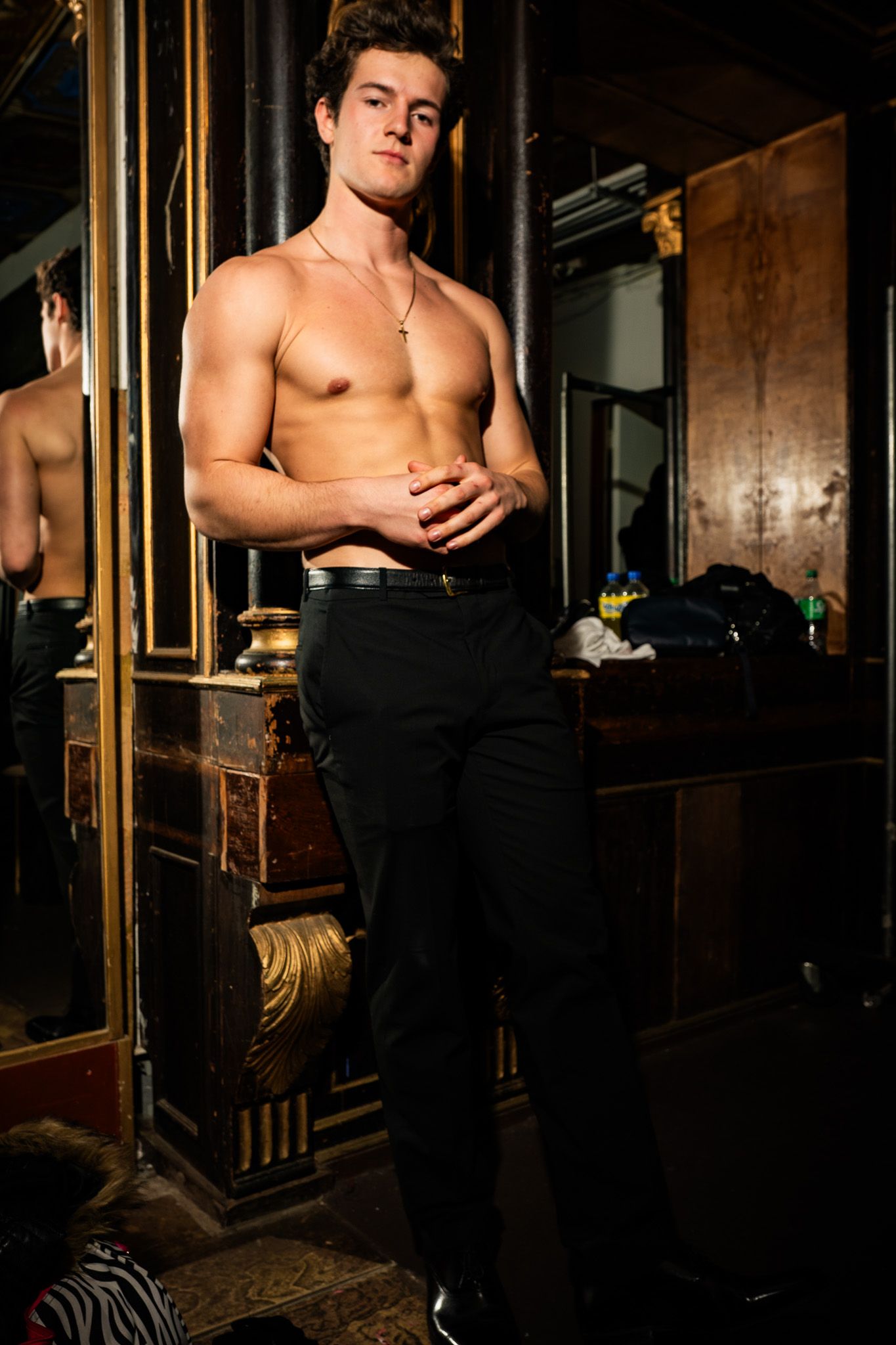 Shirtless figure poses against dark background with dramatic lighting and industrial elements.