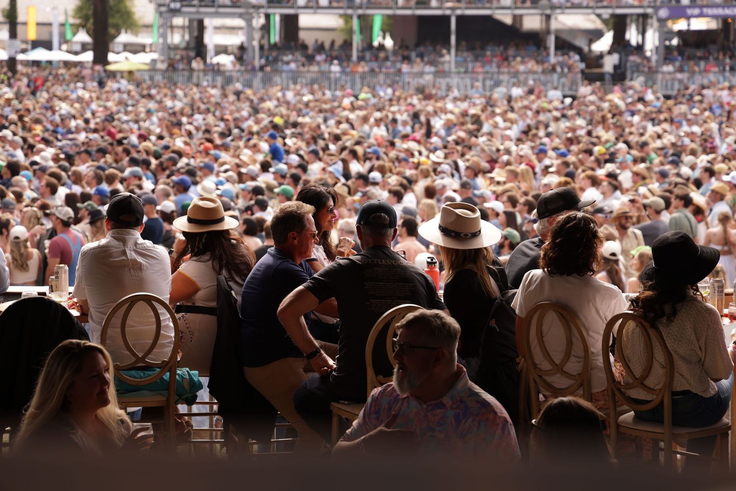 A panoramic view of a massive crowd at an outdoor concert or festival with spectators stretching into the distance.
