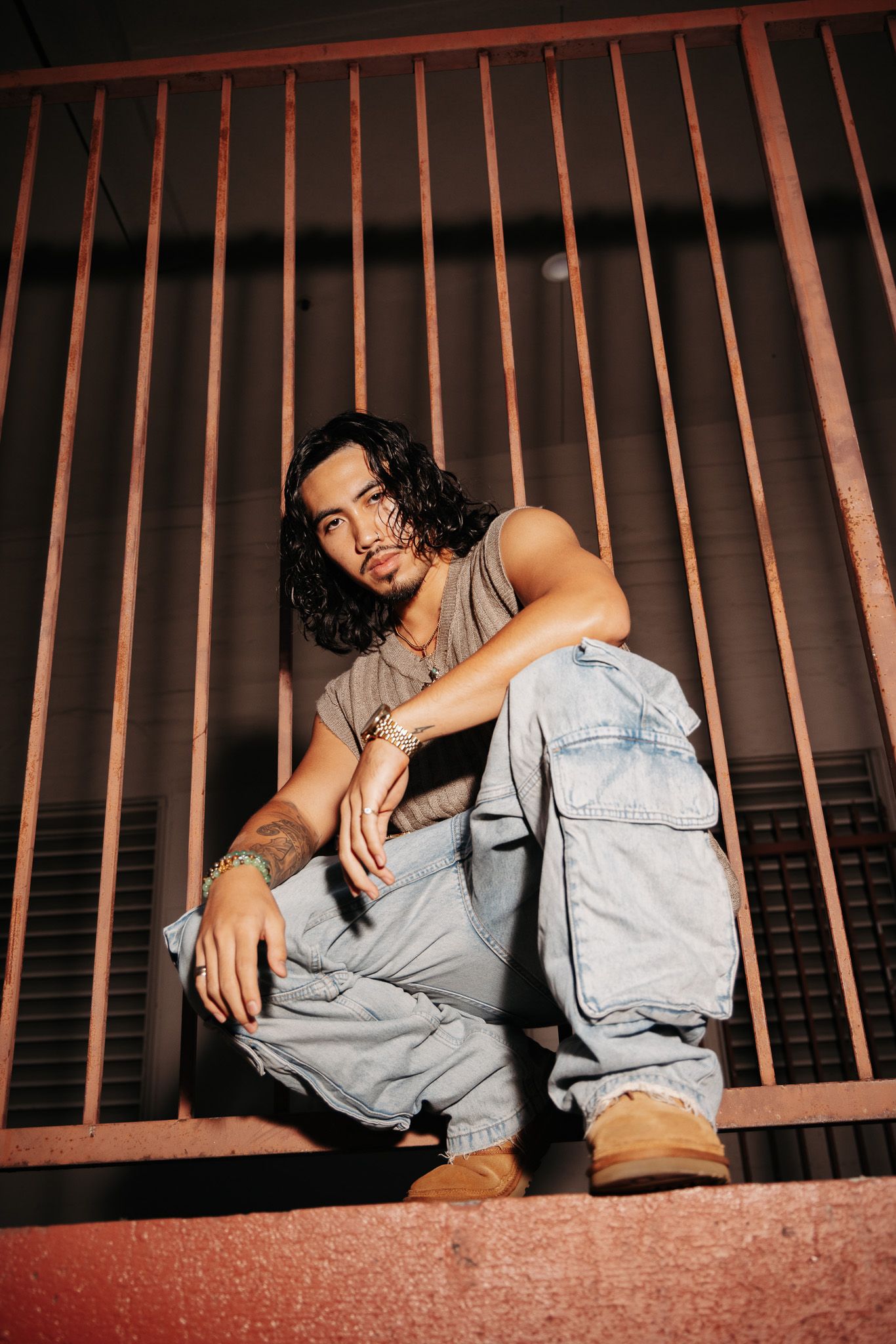 A sequence of artistic photographs showing a person in gray clothing resting against metal railings in different poses.