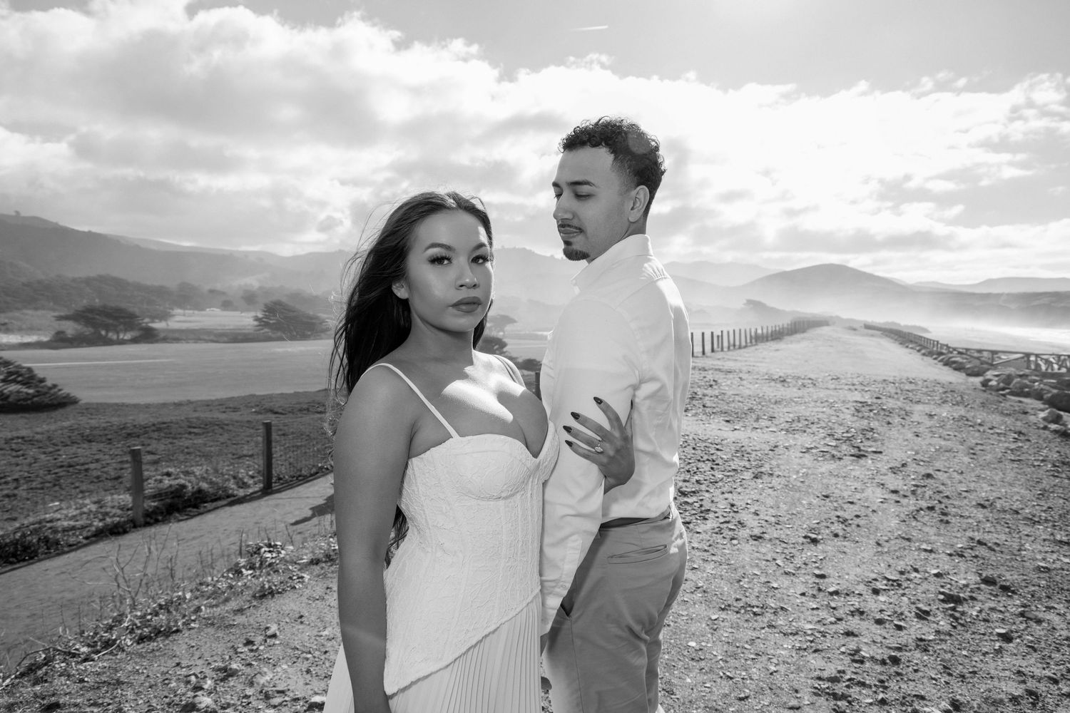 Black and white panoramic sequence of a romantic couple embracing on a scenic mountain overlook with dramatic clouds.