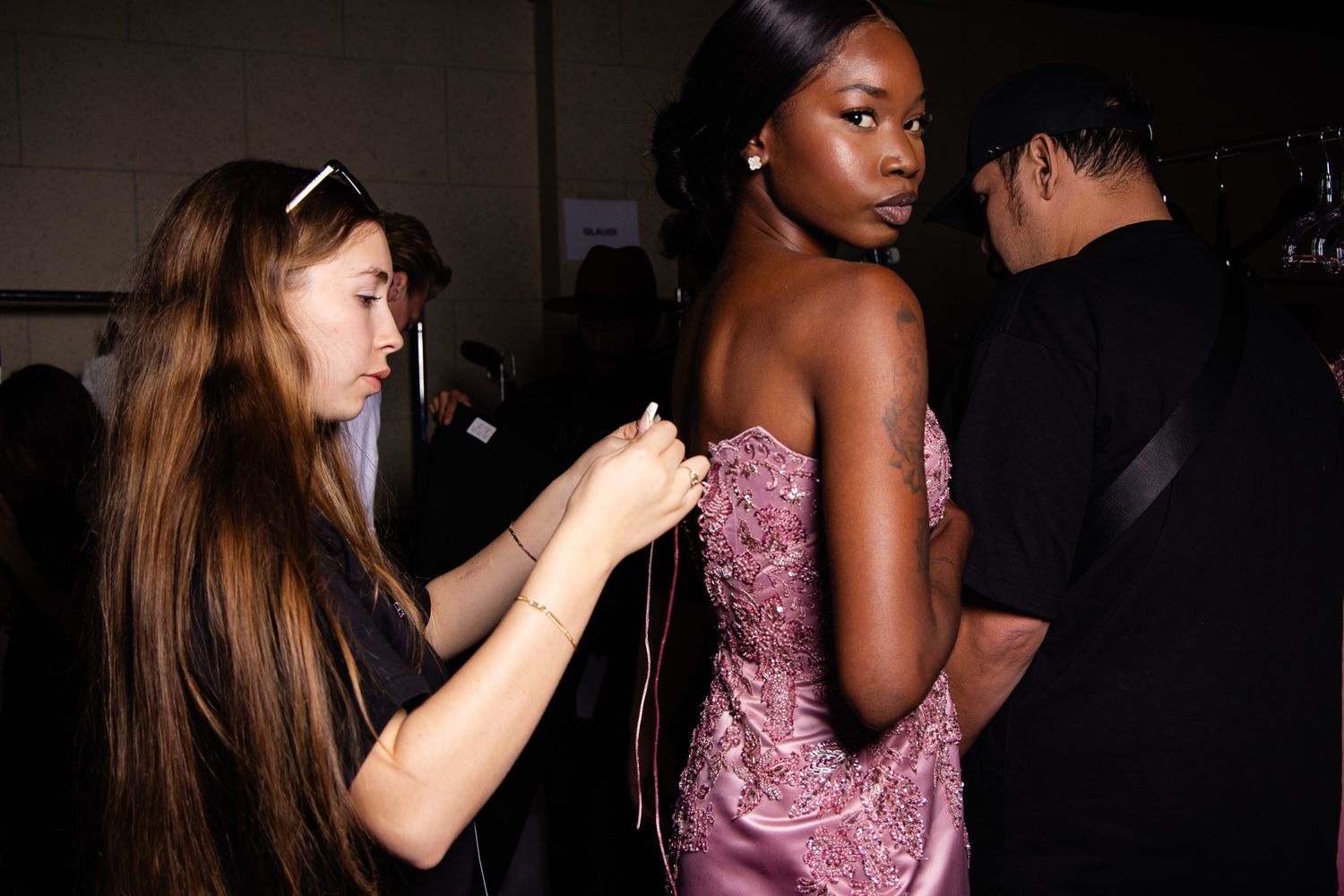 Two people dancing together in a dimly lit room with one wearing a sparkly pink dress.