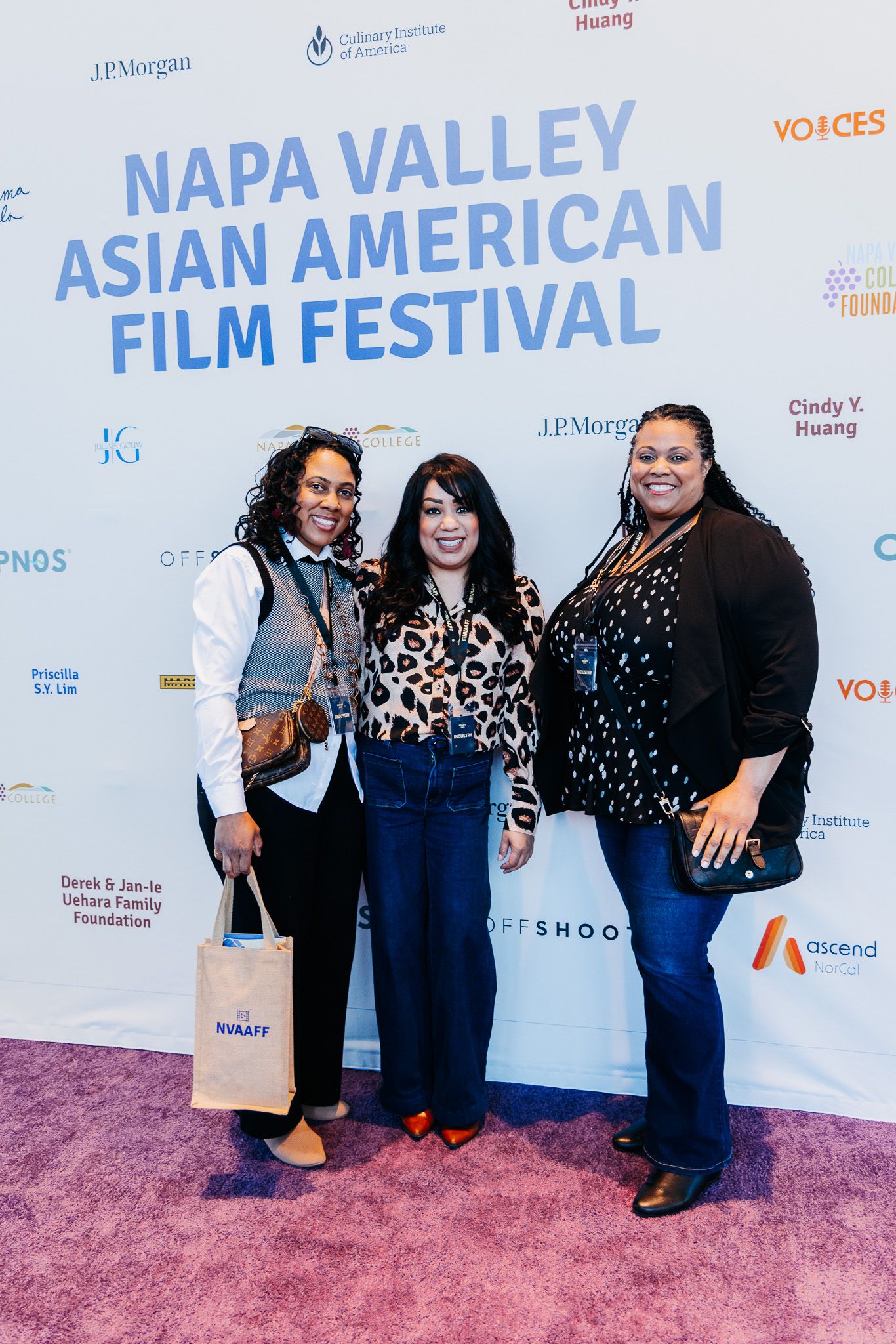 Three attendees pose on the pink carpet at the Napa Valley Asian American Film Festival entrance backdrop.