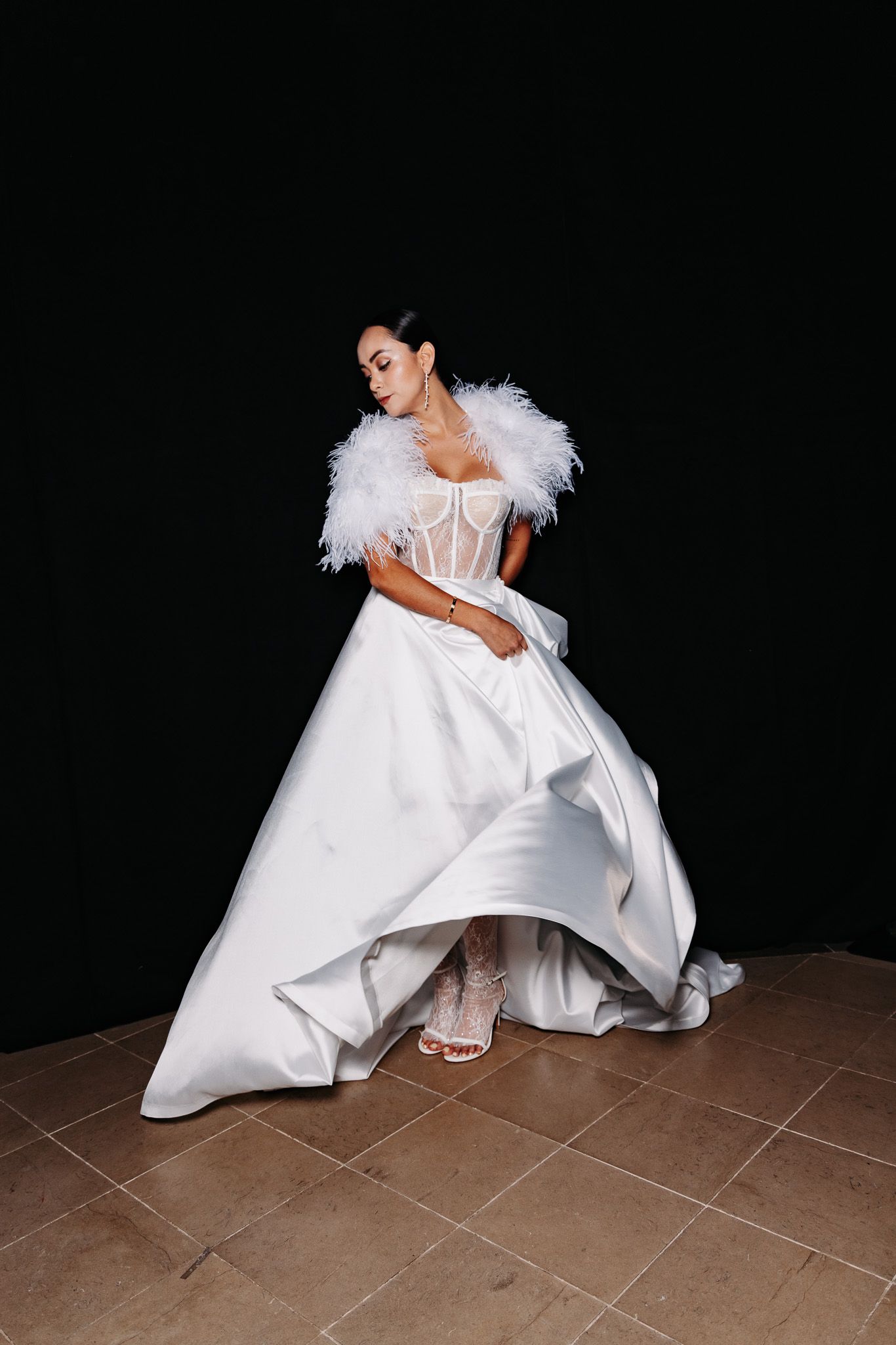 A series of fashion photos showing someone in a dramatic white gown with feather details on tiled floor.
